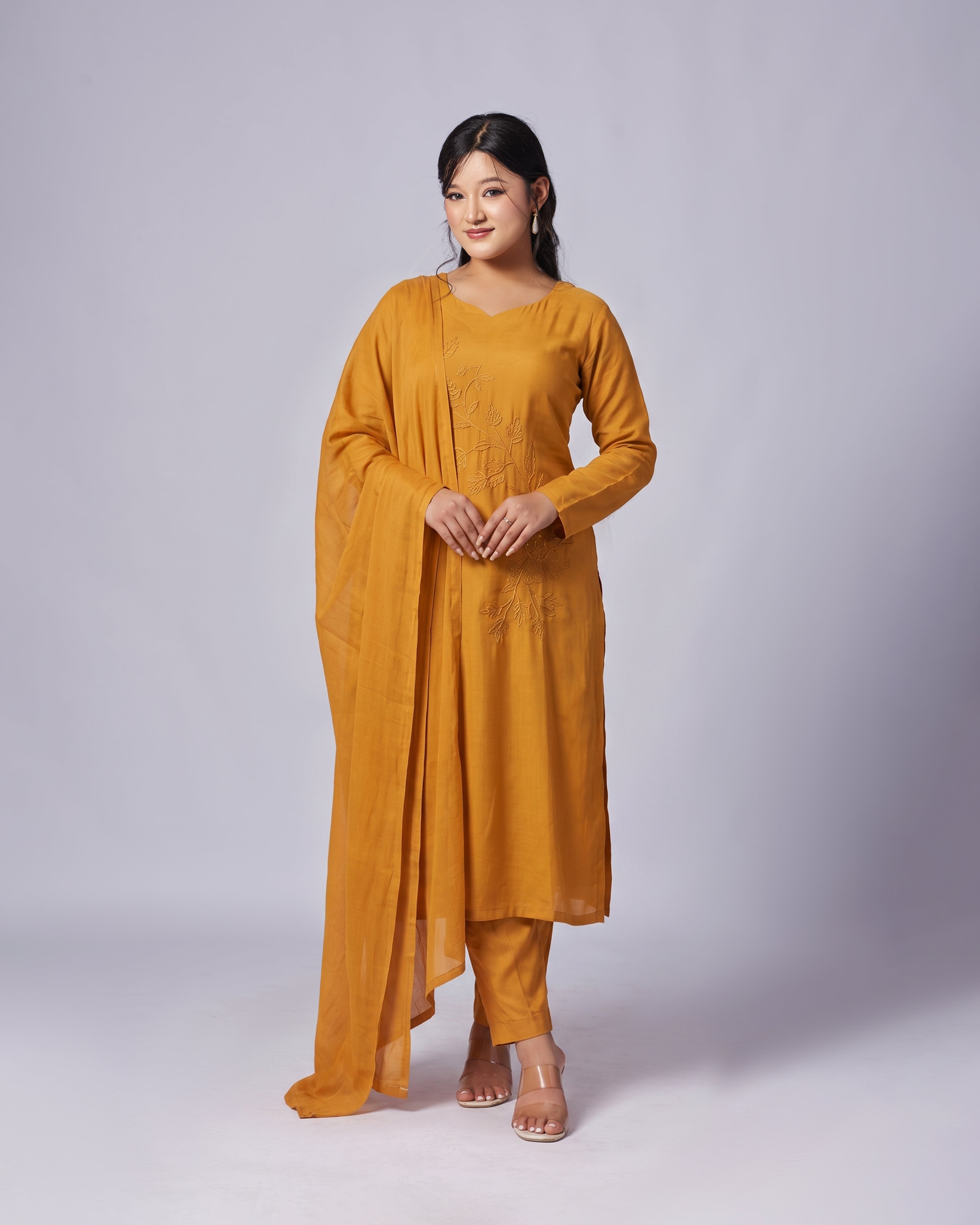 Woman wearing a mustard yellow outfit on a white background