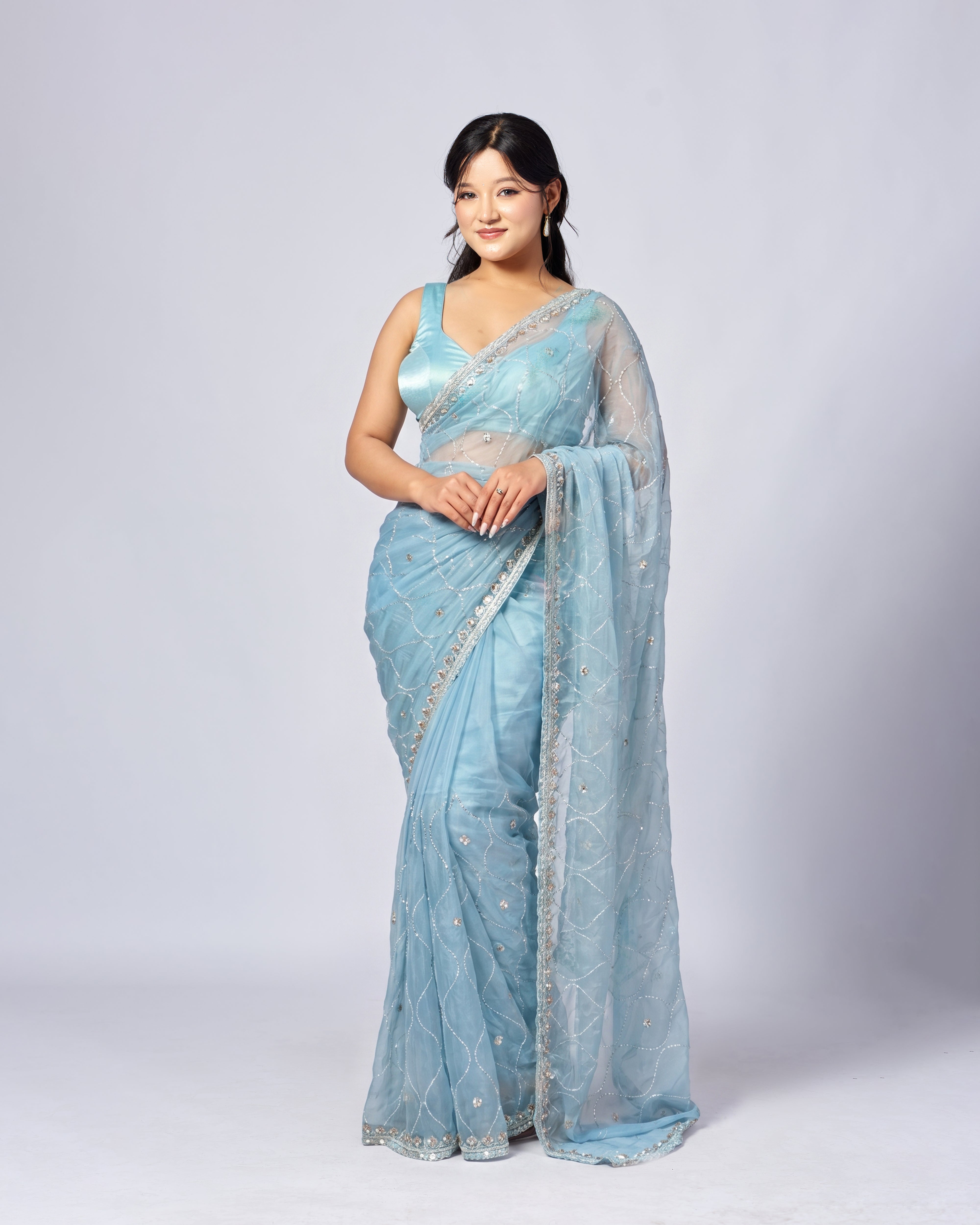 Woman wearing a light blue saree with a white background