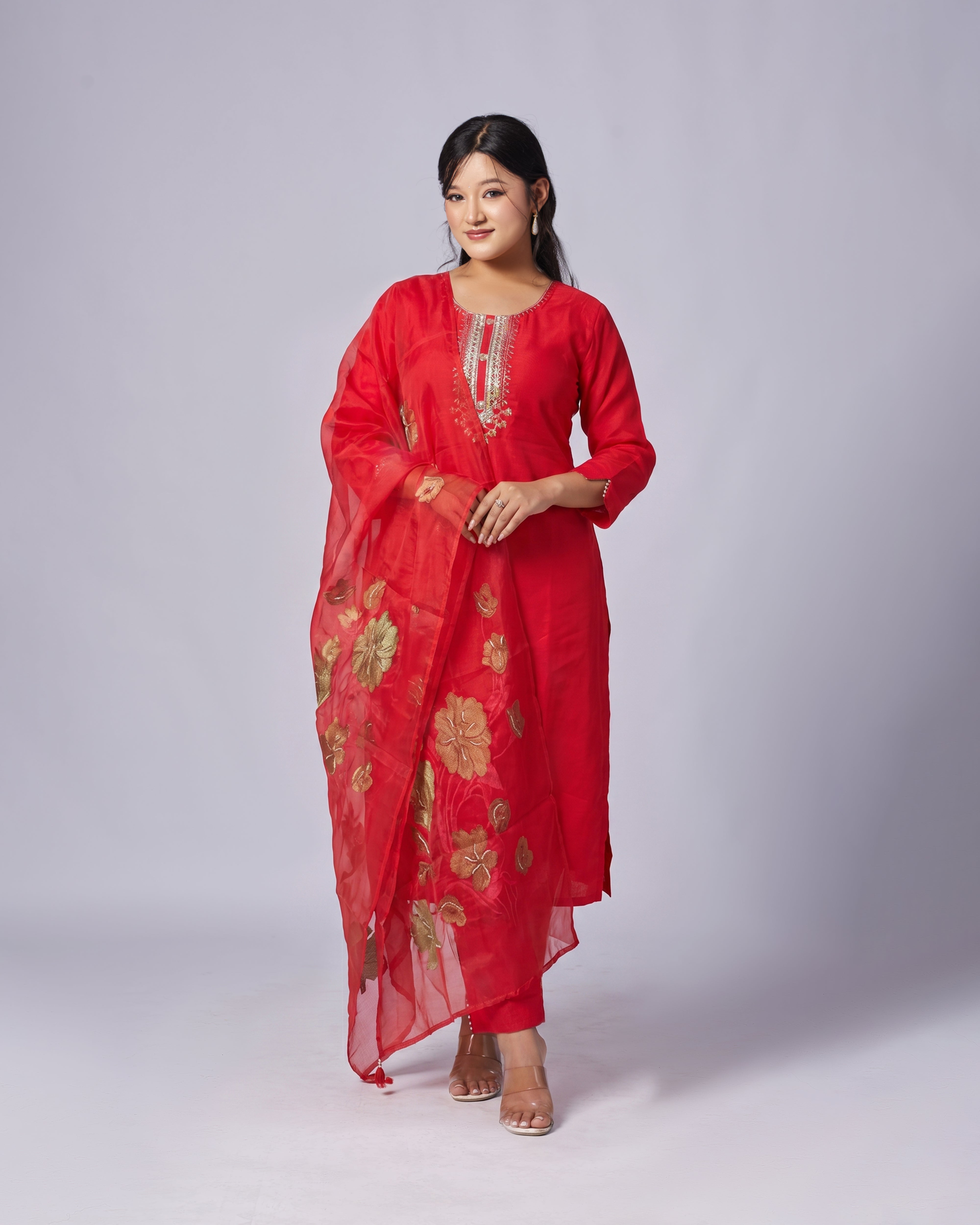 Woman wearing a red traditional outfit with floral patterns on a white background