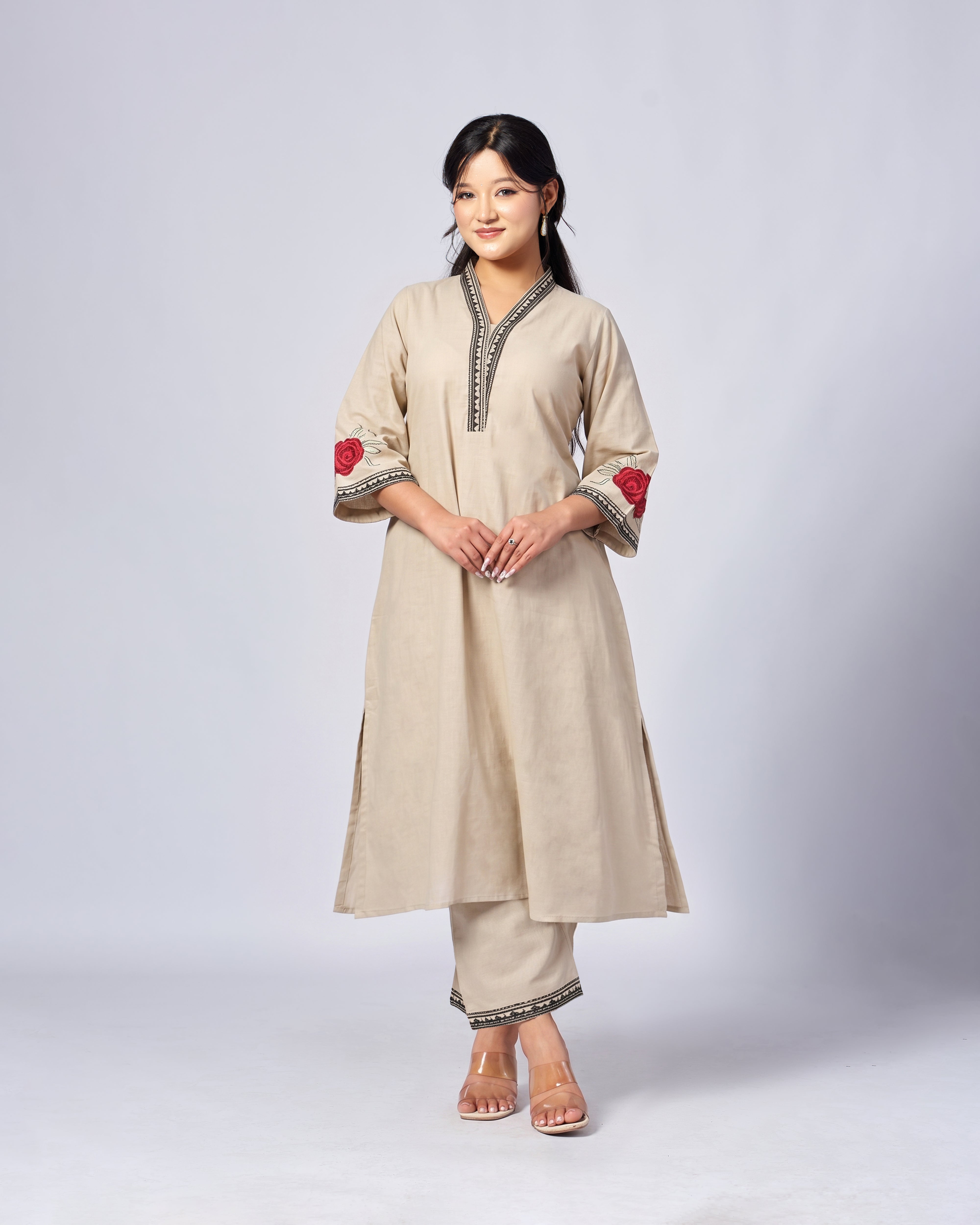 Woman wearing a beige traditional outfit with red accents on a white background
