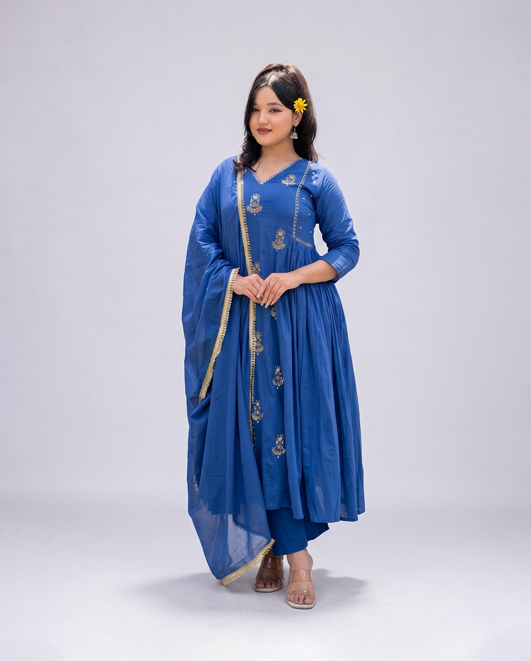Woman wearing a blue traditional outfit with gold accents on a white background