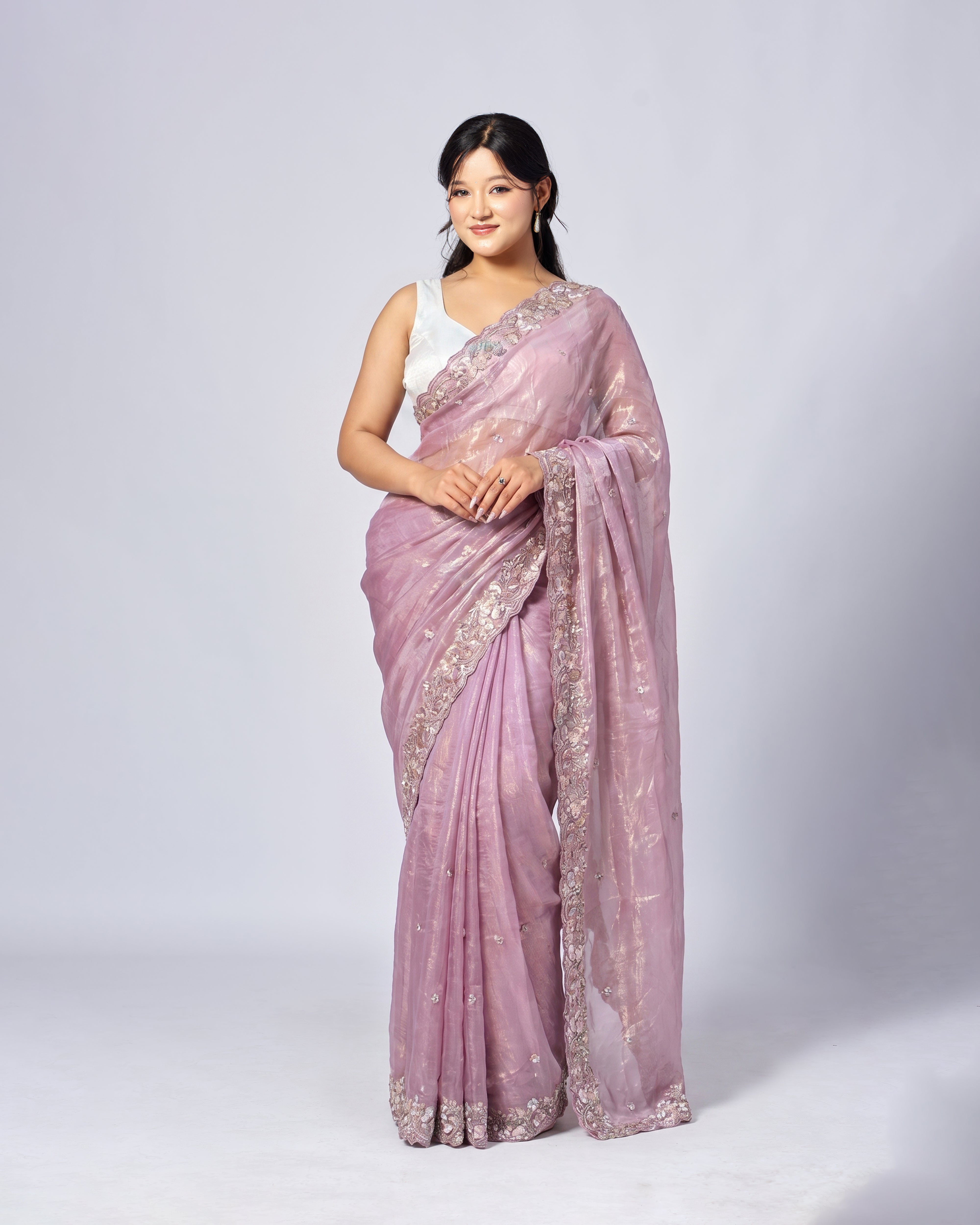 Woman wearing a pink saree with white patterns on a white background