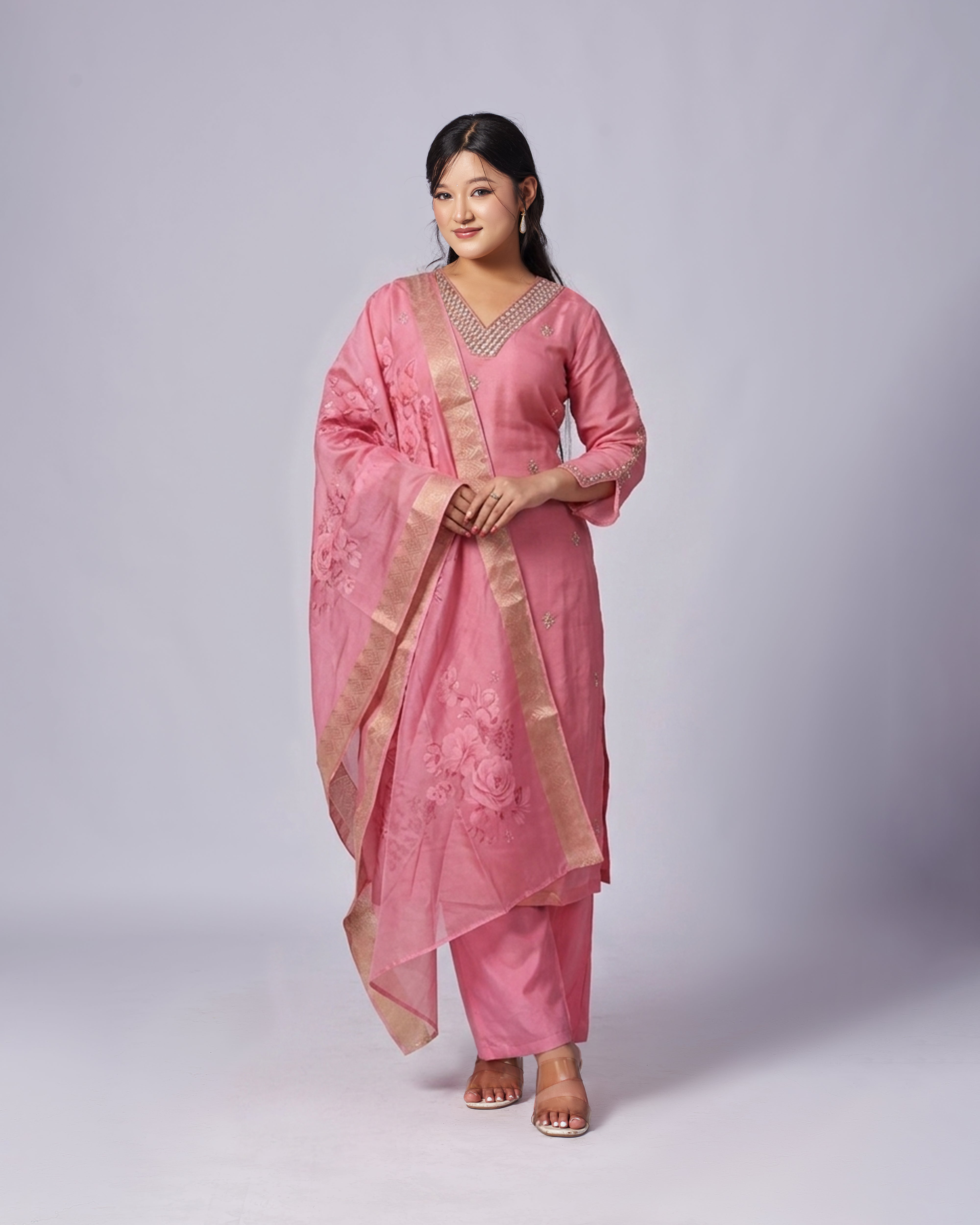 Woman wearing a pink traditional outfit with a matching dupatta on a white background