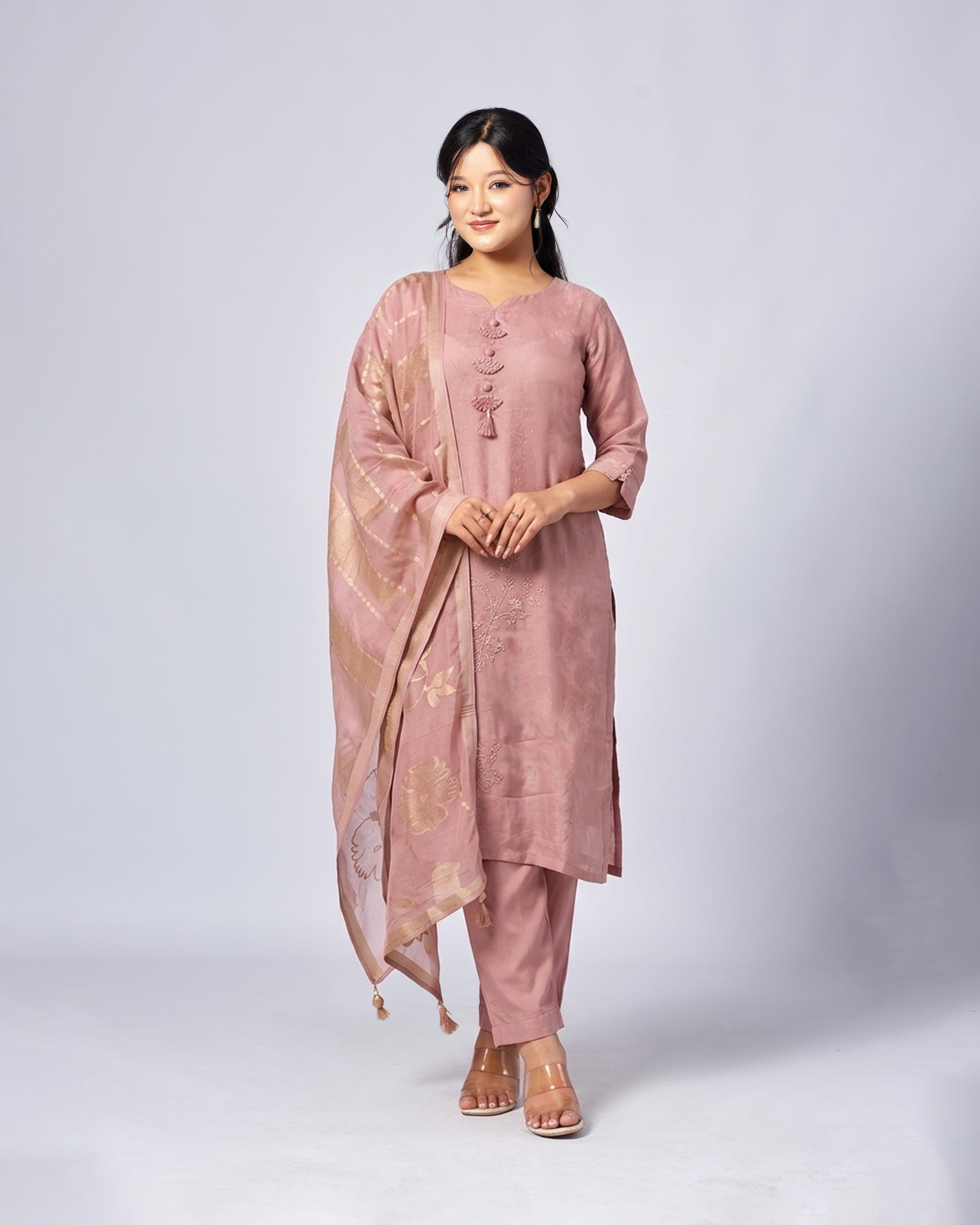 Woman wearing a pink traditional outfit with a matching dupatta on a white background