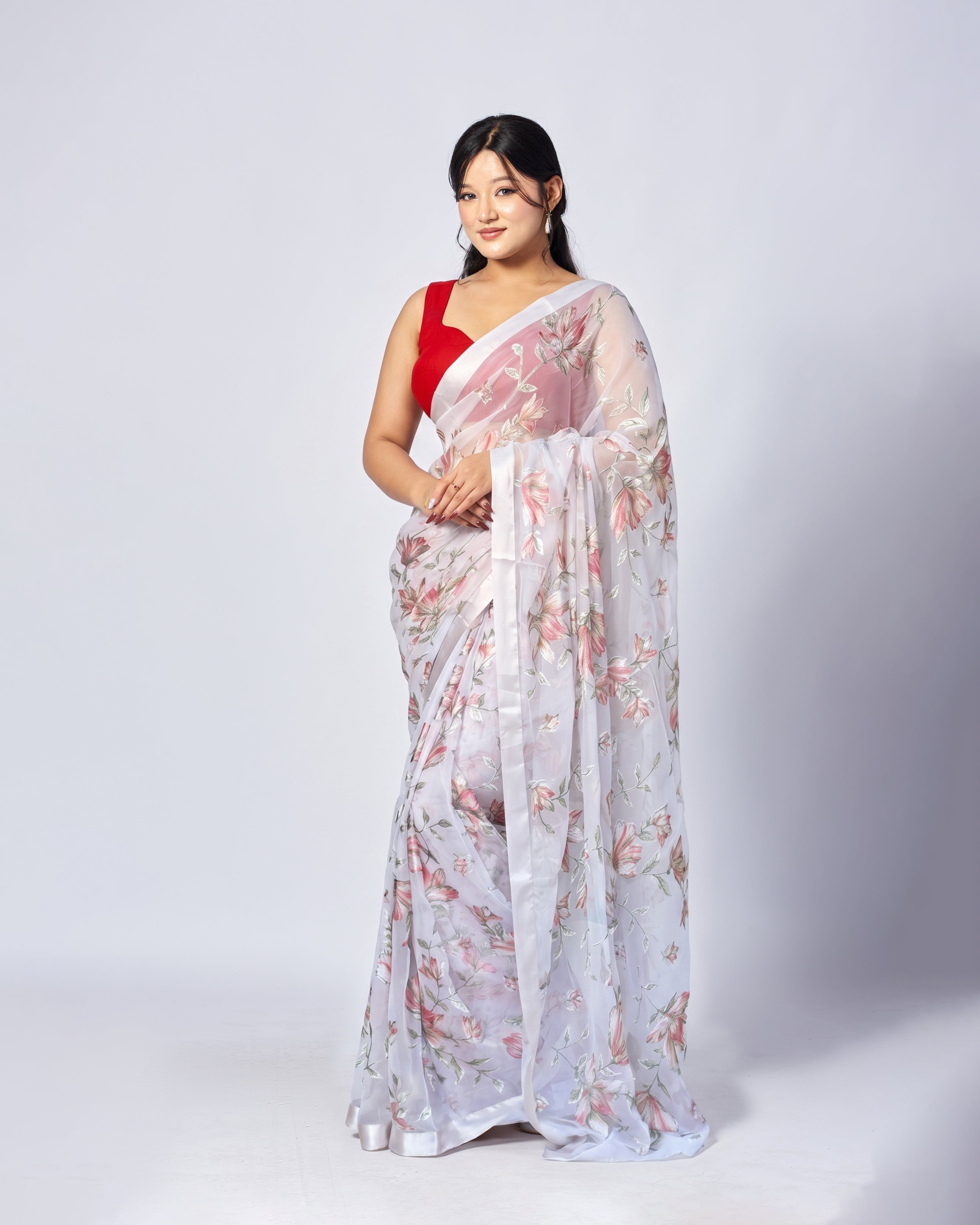 Woman wearing a white floral saree with a red blouse on a white background