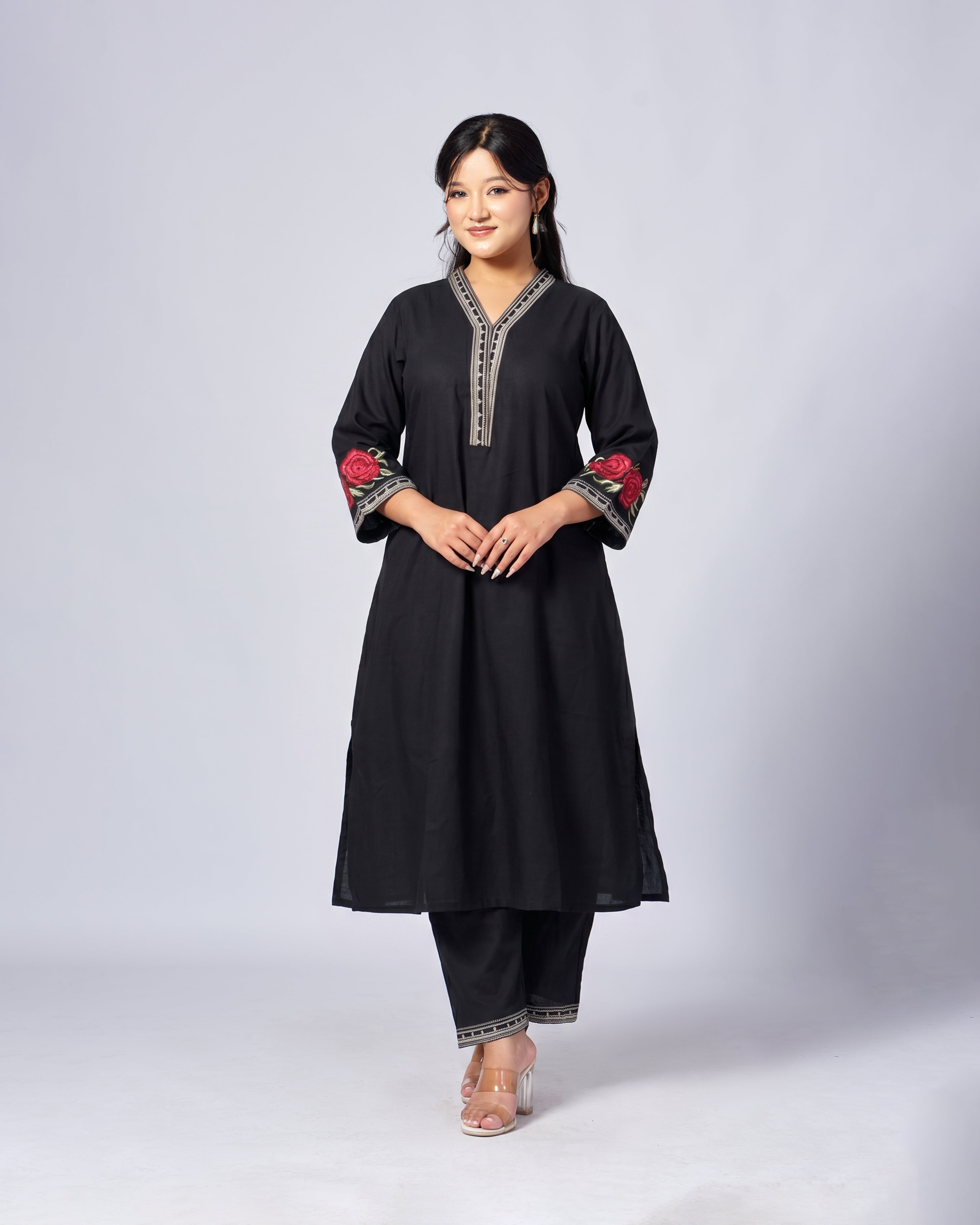 Woman wearing a black traditional outfit with floral embroidery on a white background
