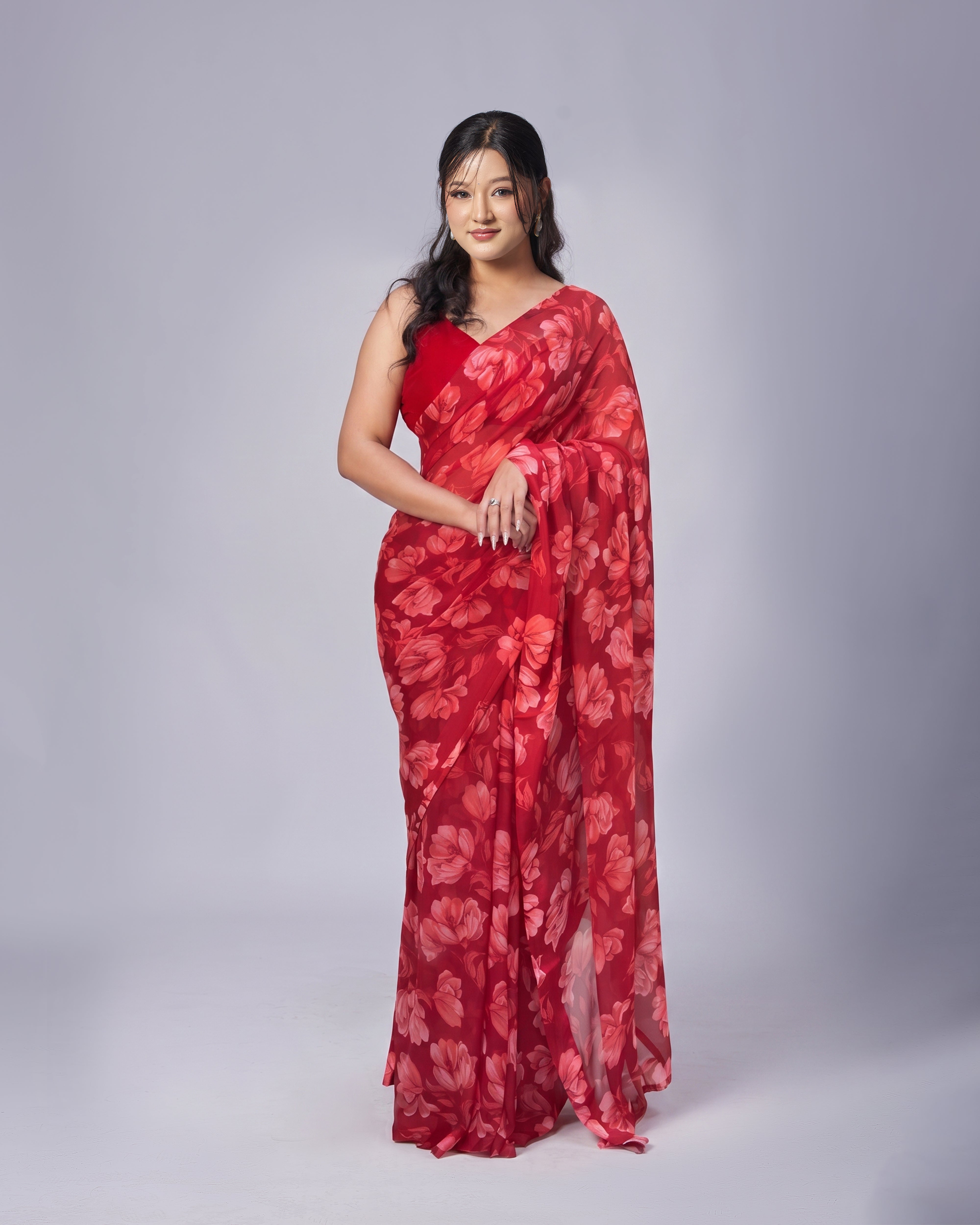 Woman wearing a red floral saree against a gray background