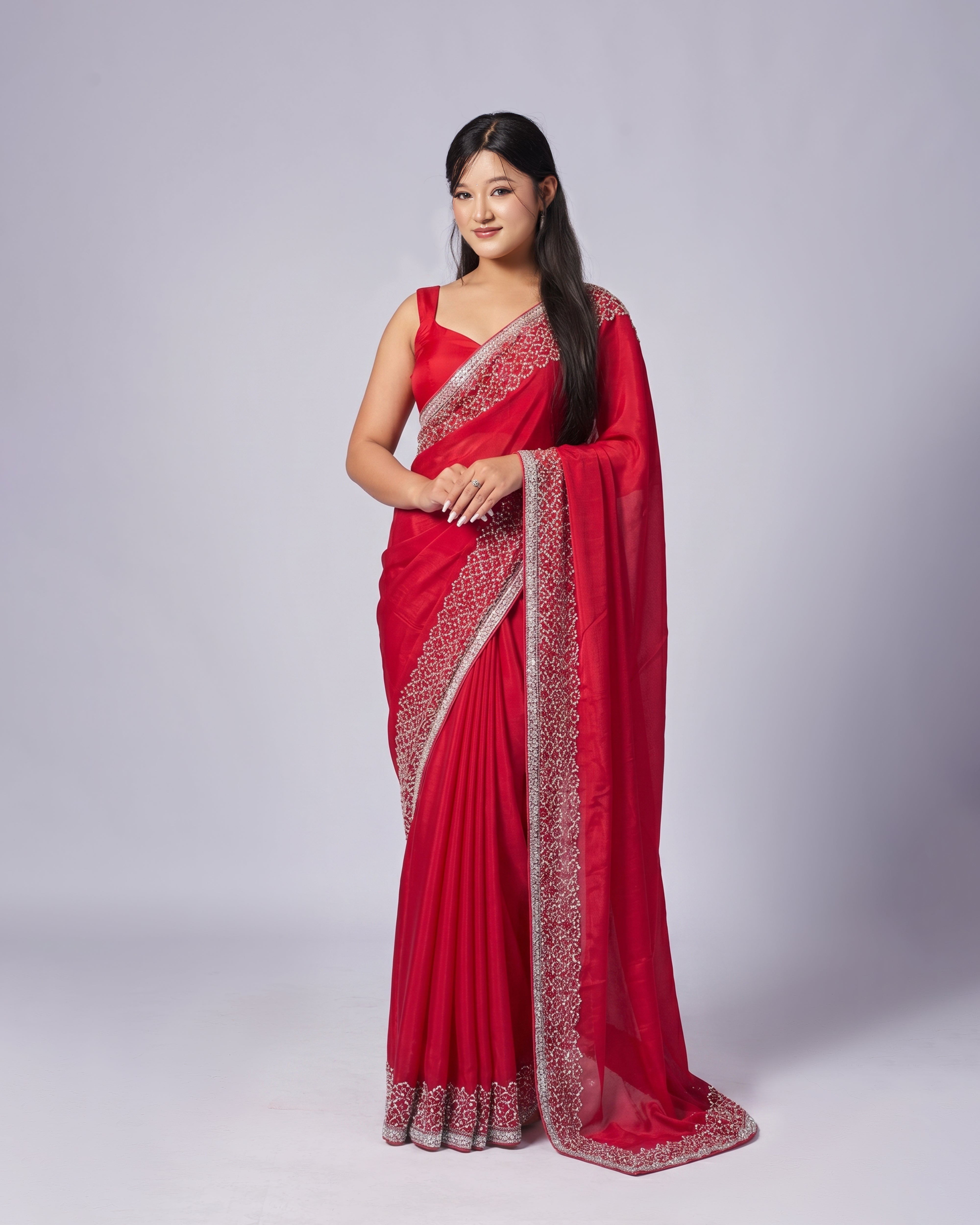 Woman wearing a red saree with white border on a gray background