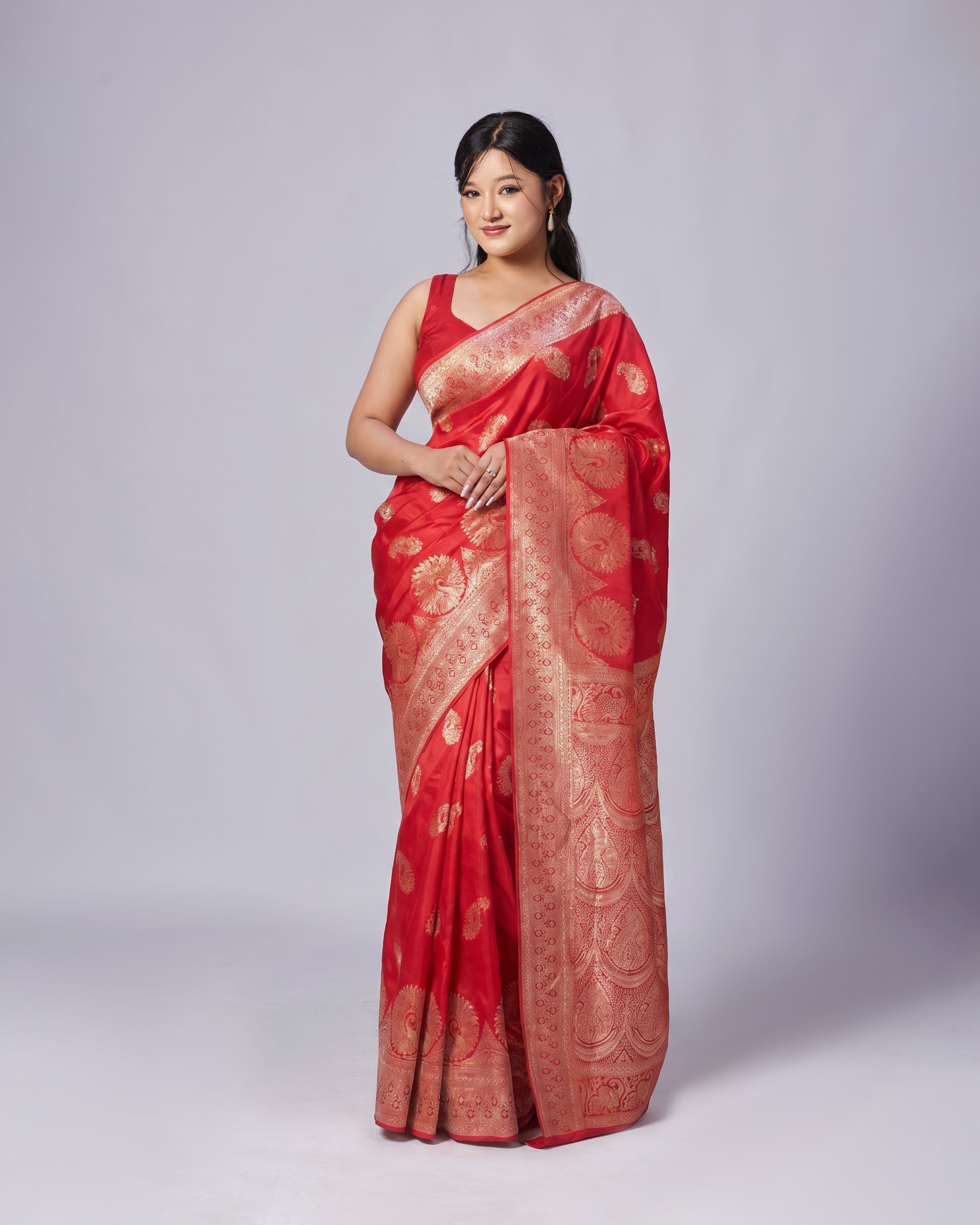 Woman wearing a red saree with gold patterns on a white background