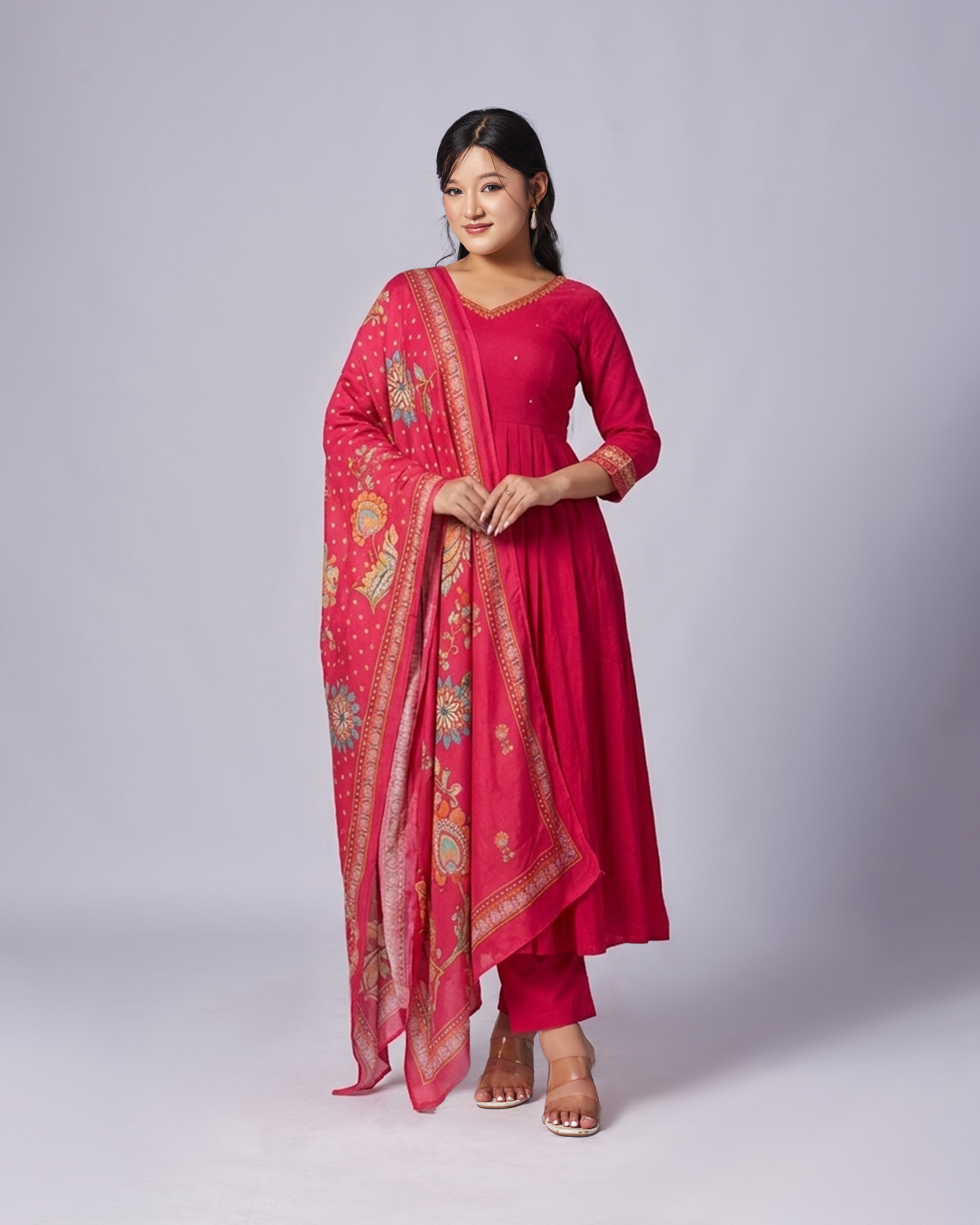 Woman wearing a pink traditional outfit with a matching dupatta on a white background