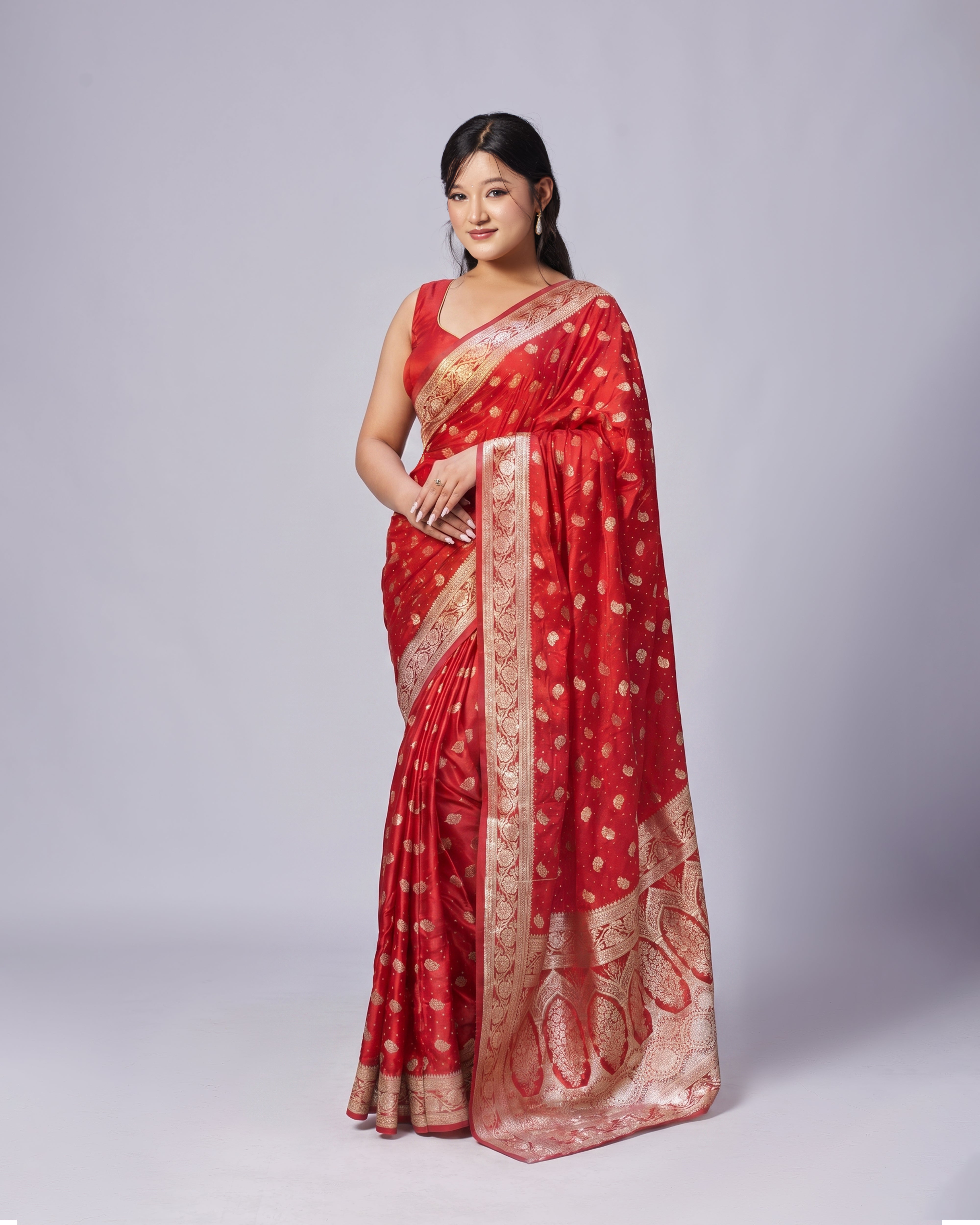 Woman wearing a red saree with gold patterns on a white background