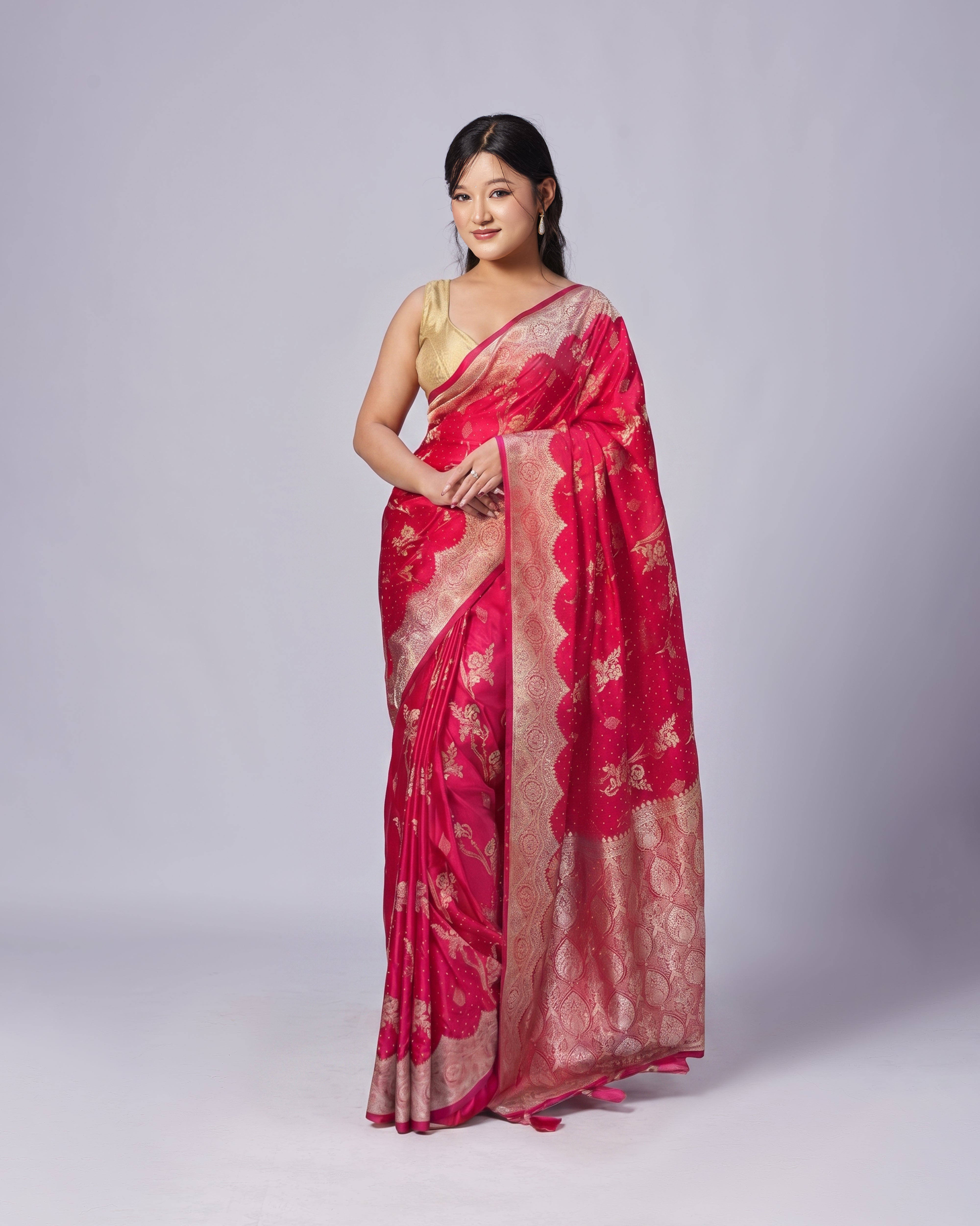 Woman wearing a red saree with gold patterns on a white background