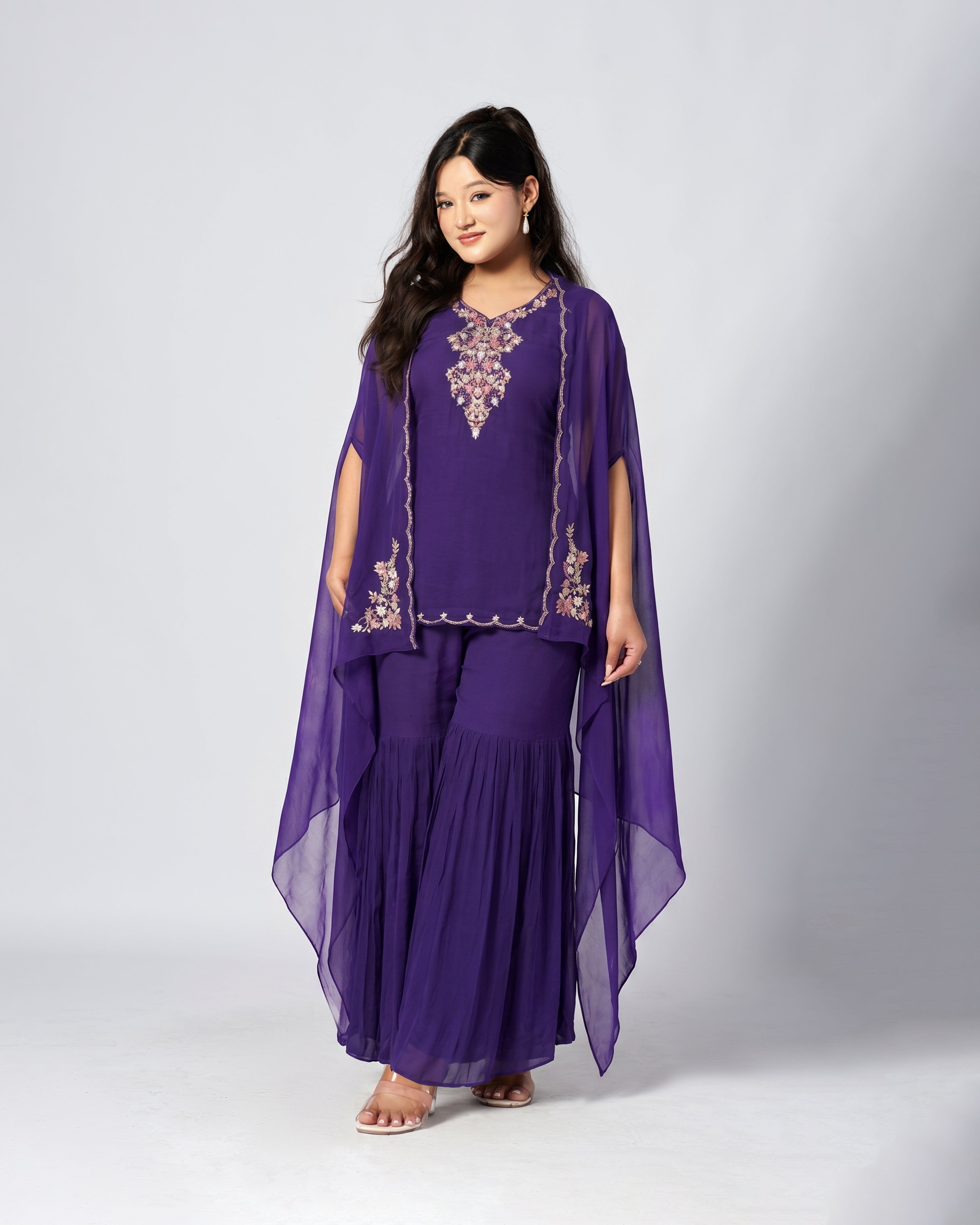 Woman wearing a purple traditional outfit with a cape on a white background