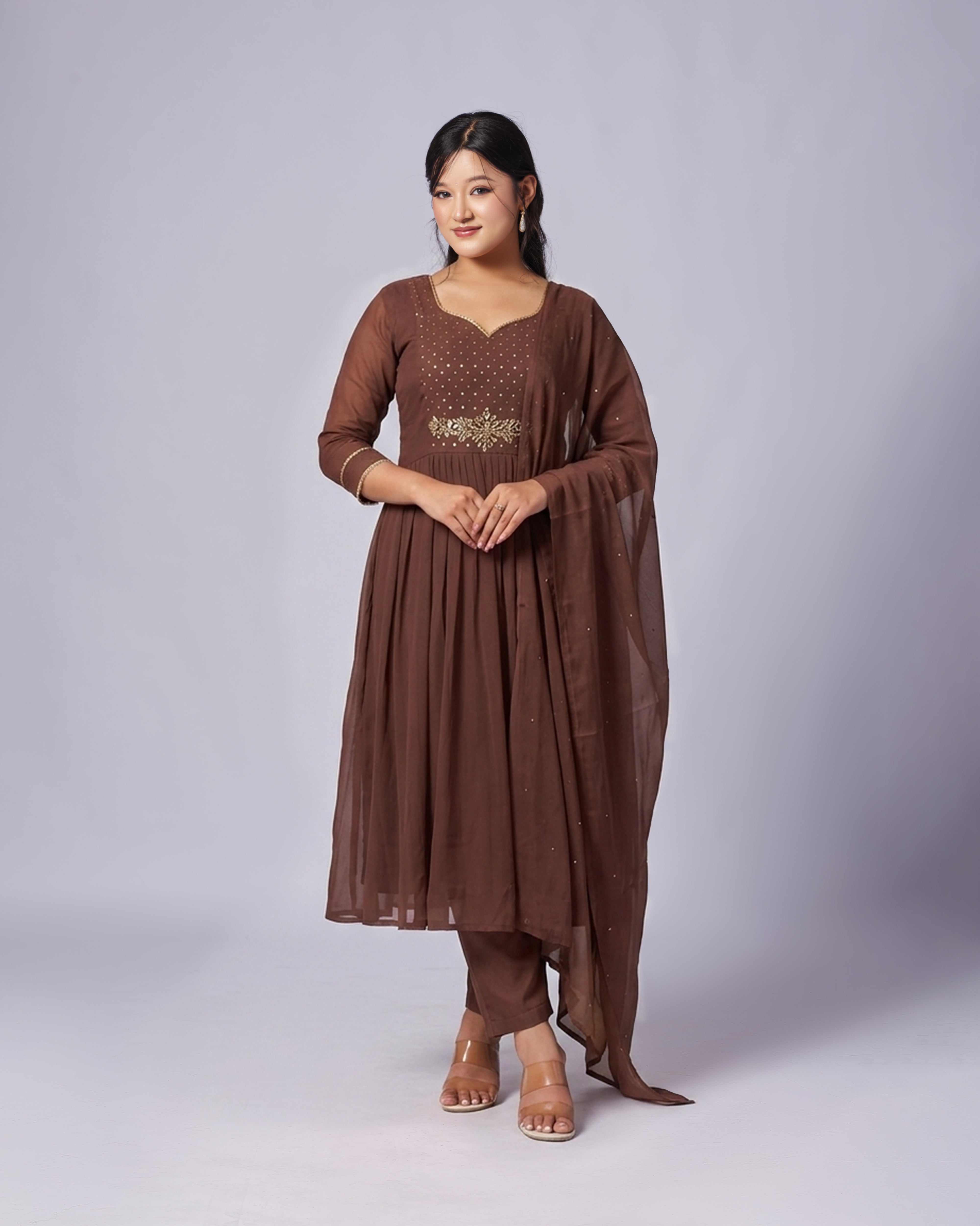 Woman wearing a brown traditional outfit with a plain background