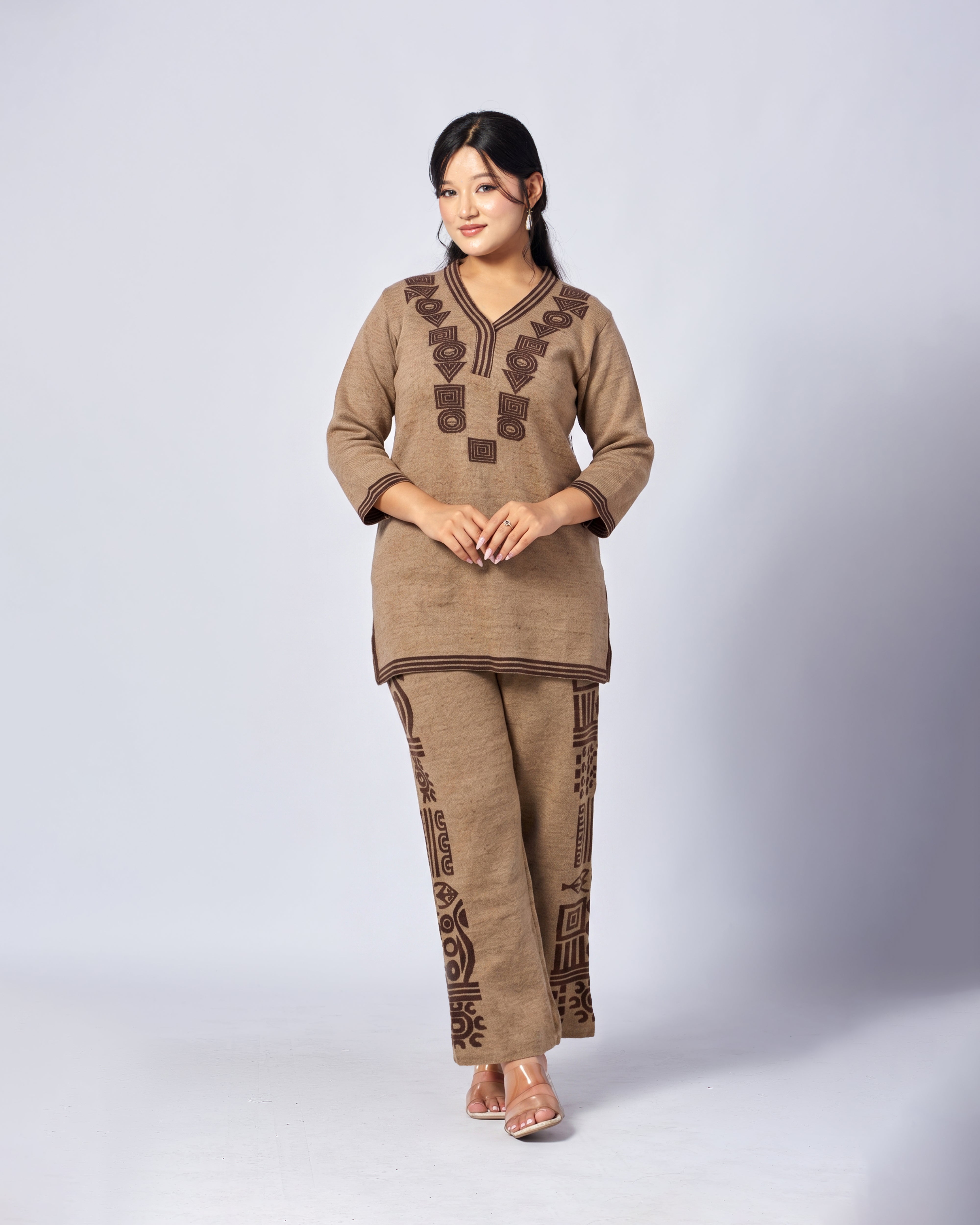 Woman wearing a brown traditional outfit with intricate patterns on a white background