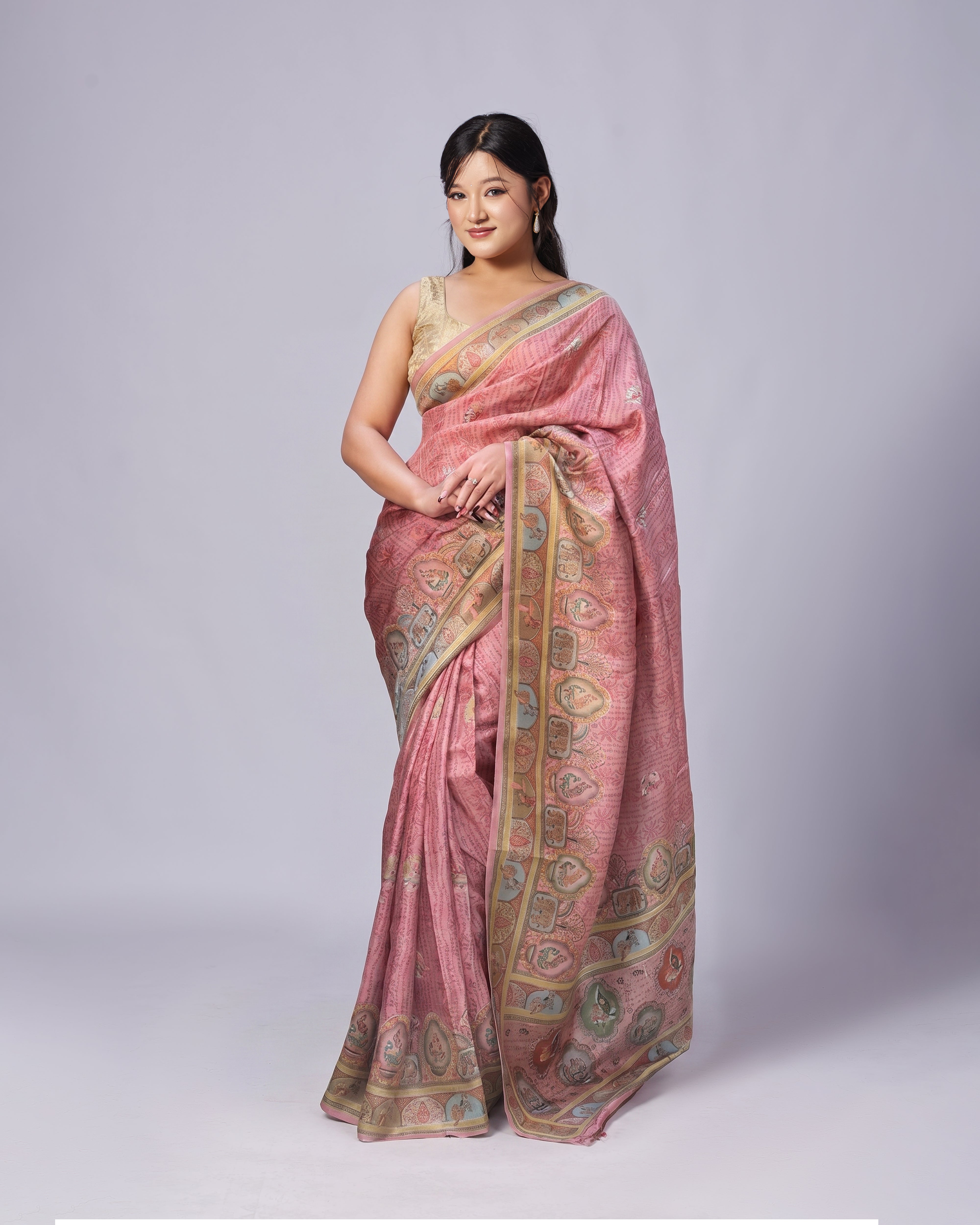 Woman wearing a pink saree with intricate patterns on a plain background