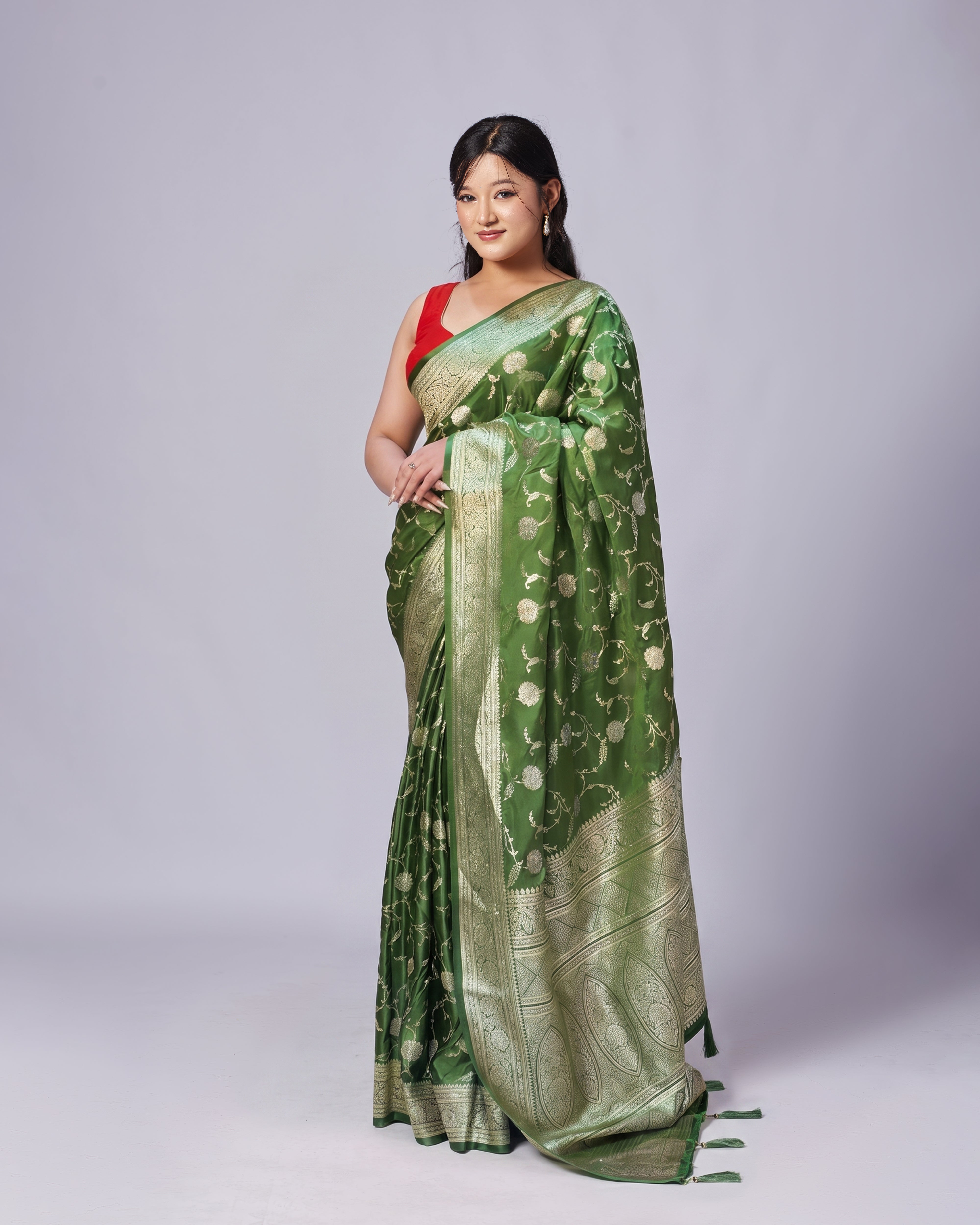 Woman wearing a green saree with a red blouse on a white background