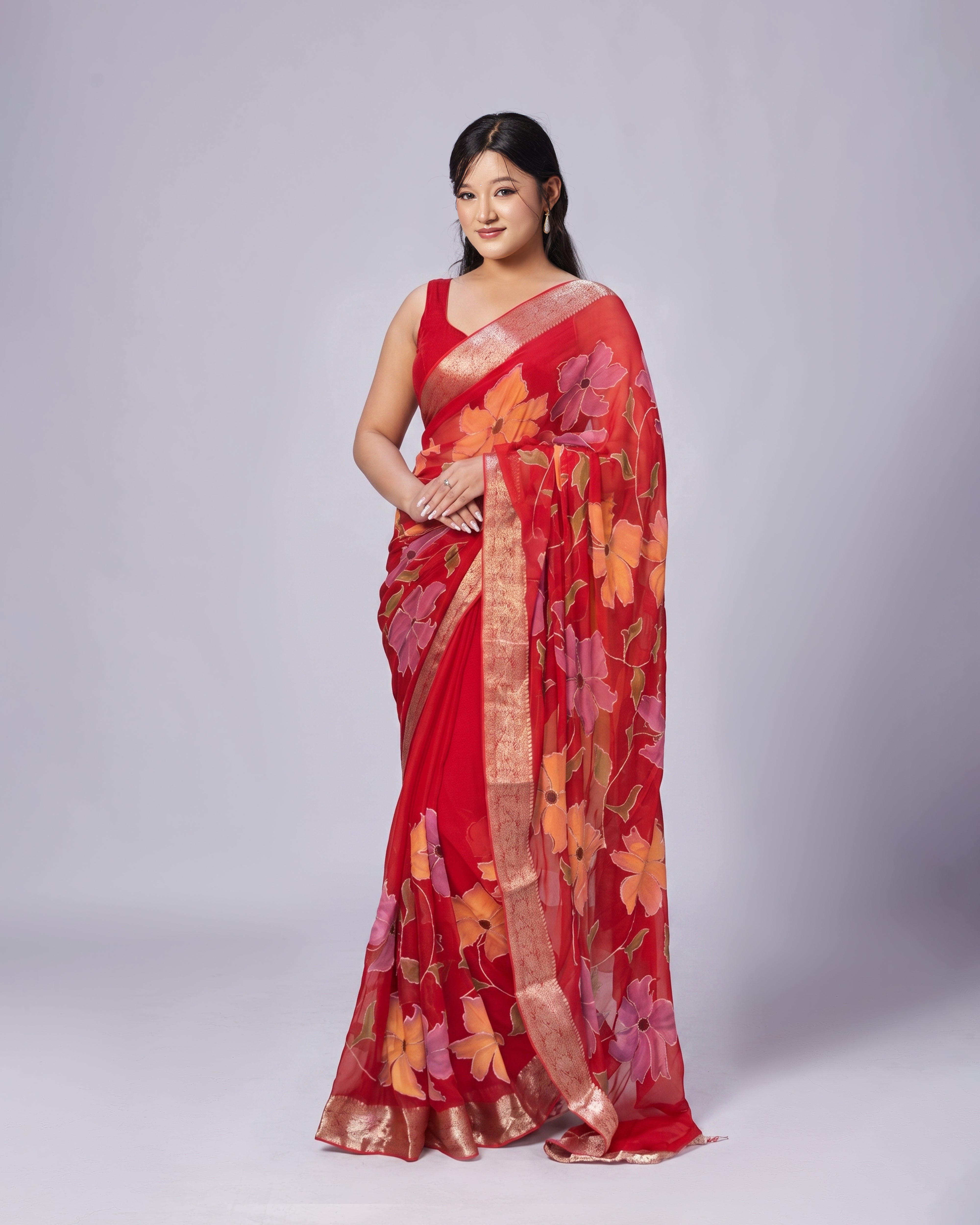 Woman wearing a red saree with floral patterns on a white background