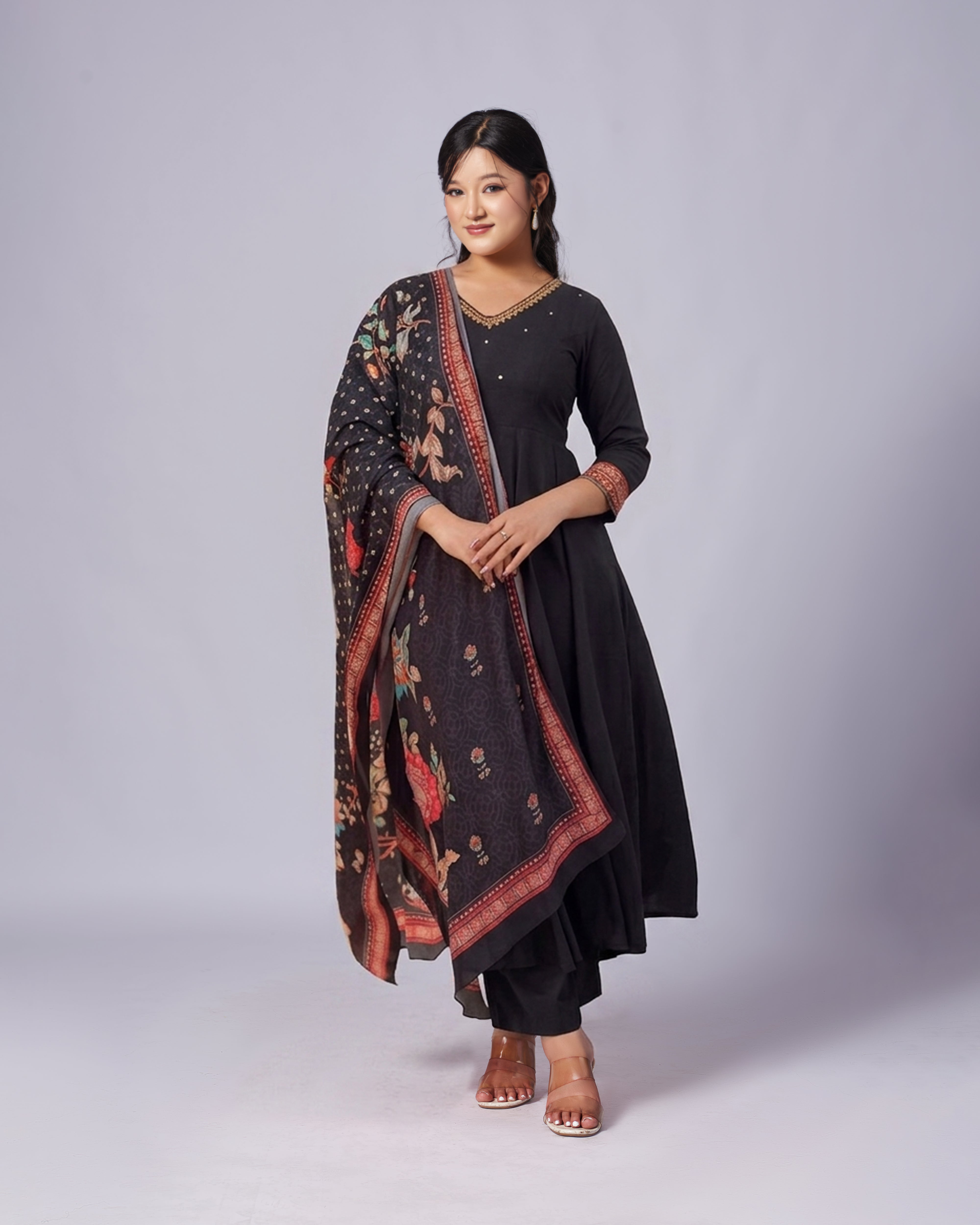 Woman wearing a black outfit with a patterned shawl on a white background