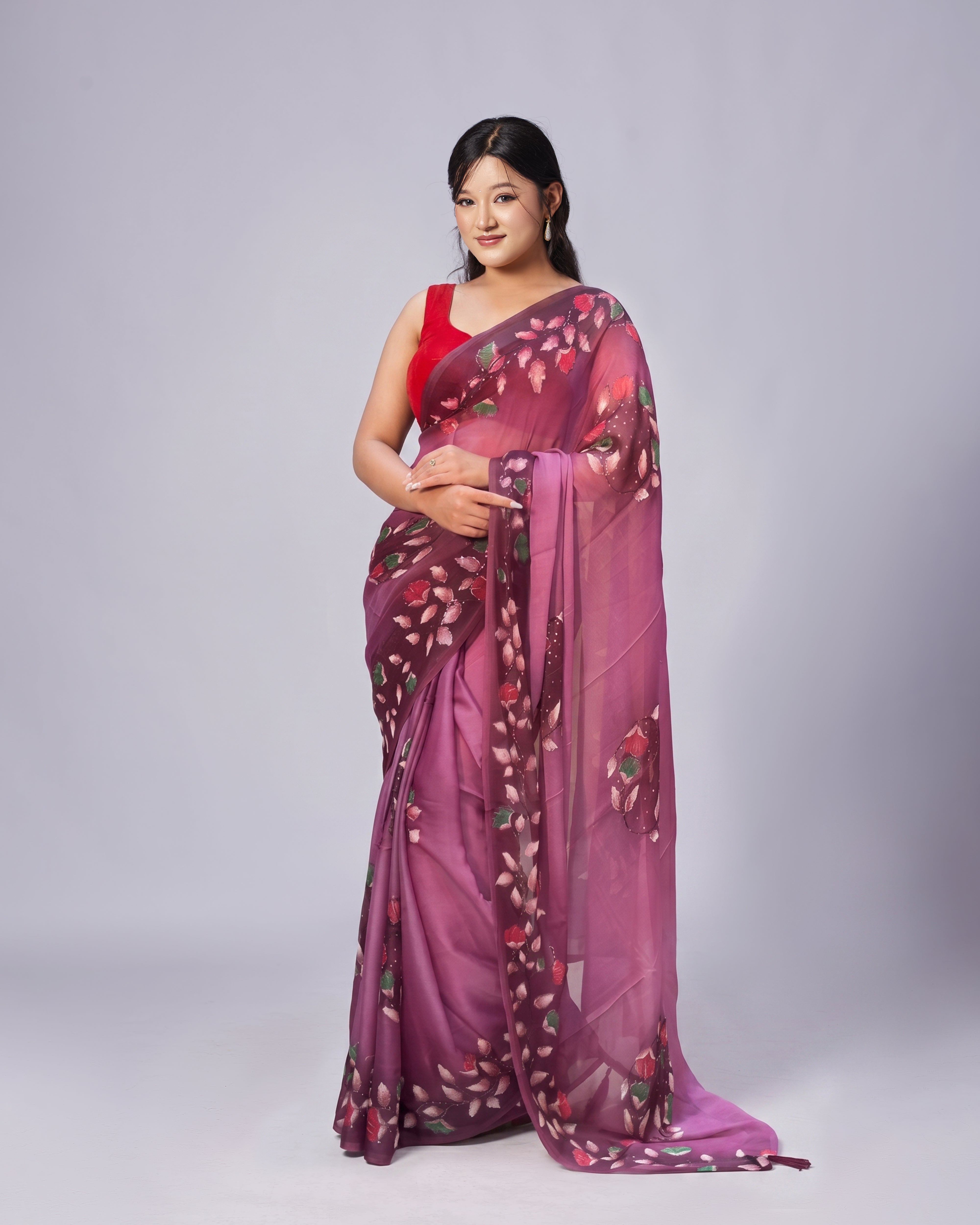 Woman wearing a purple saree with floral patterns on a plain background