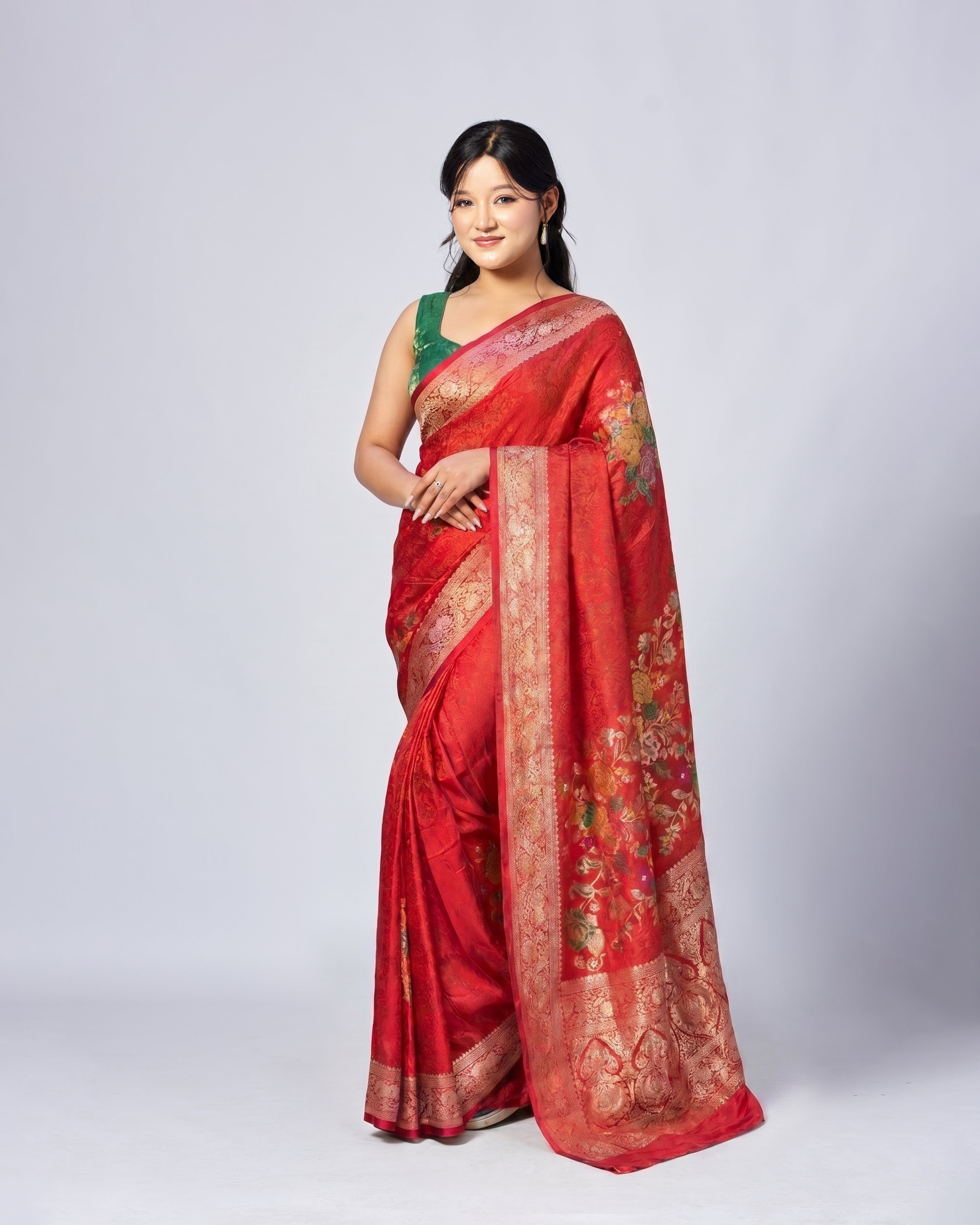 Woman wearing a red saree with gold patterns on a white background