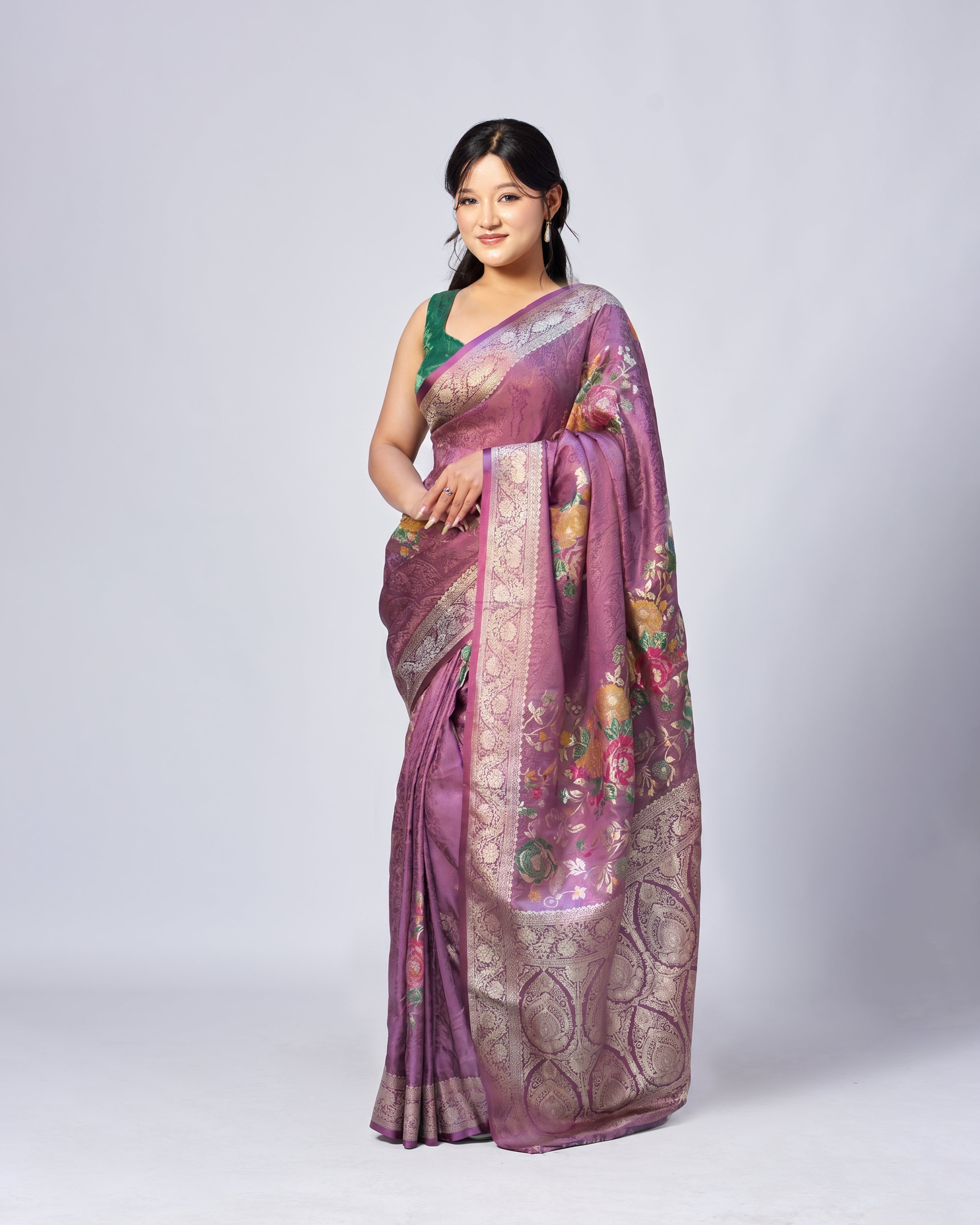 Woman wearing a purple saree with floral patterns on a white background