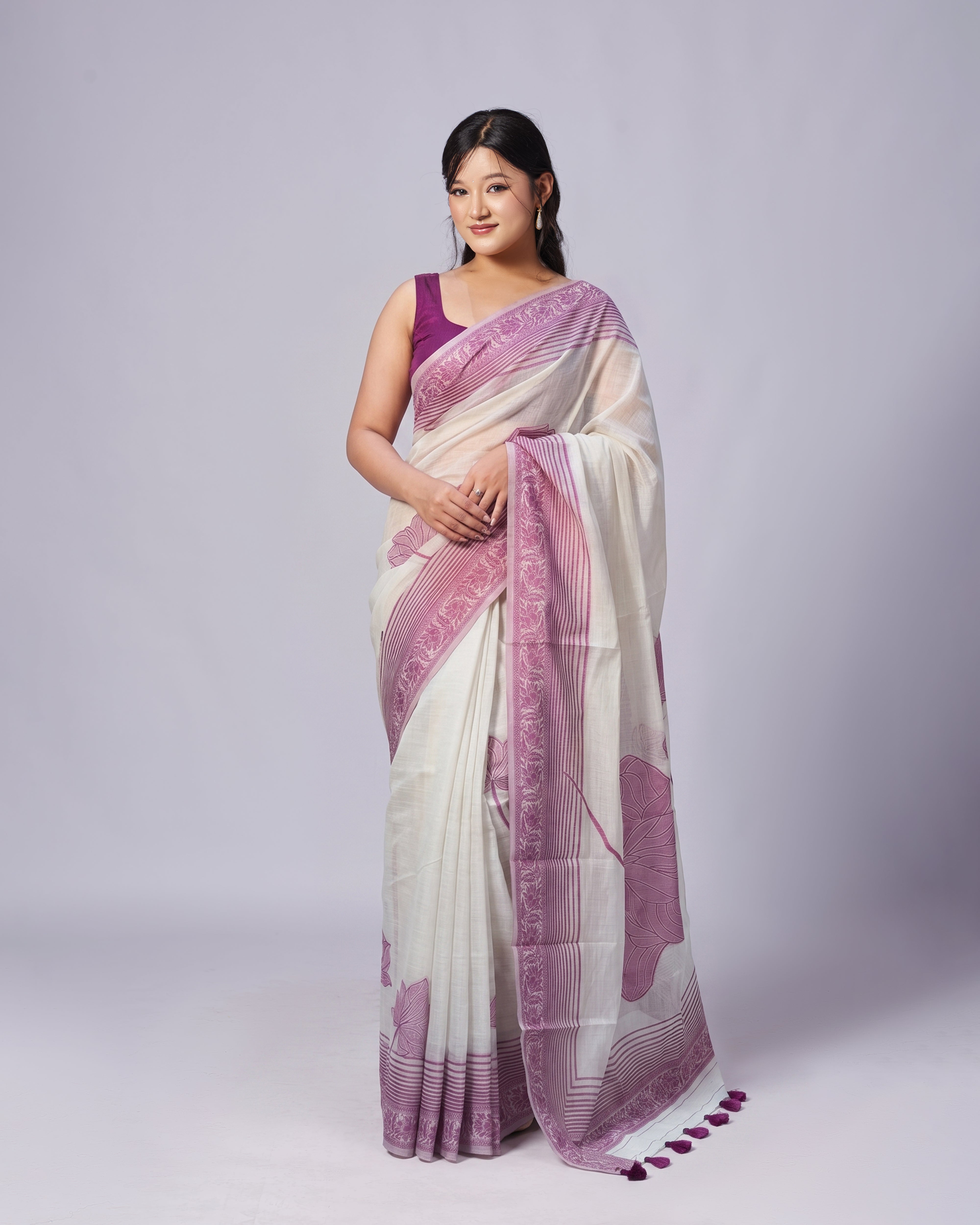 Woman wearing a white and purple saree on a gray background