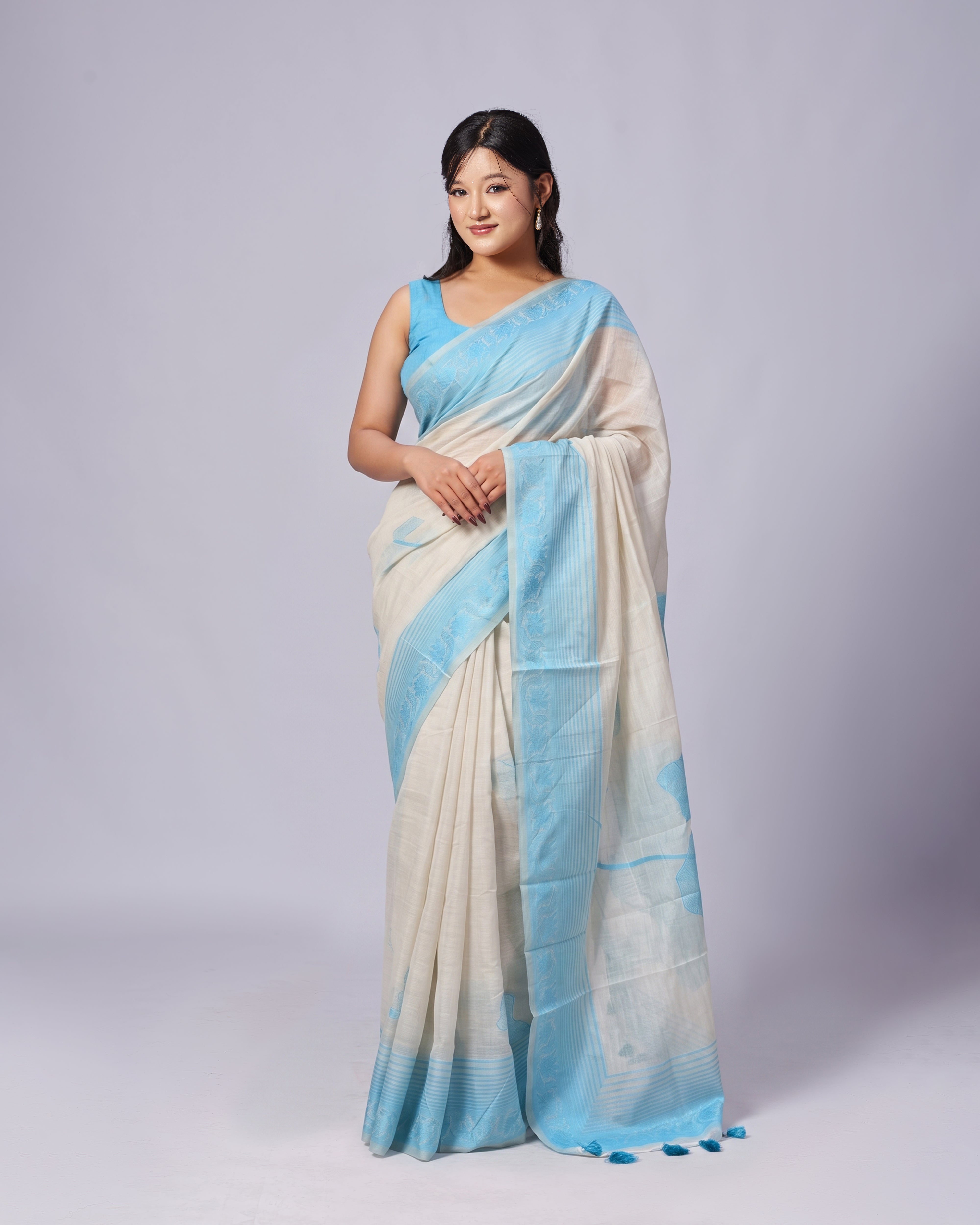 Woman wearing a blue and white saree on a gray background