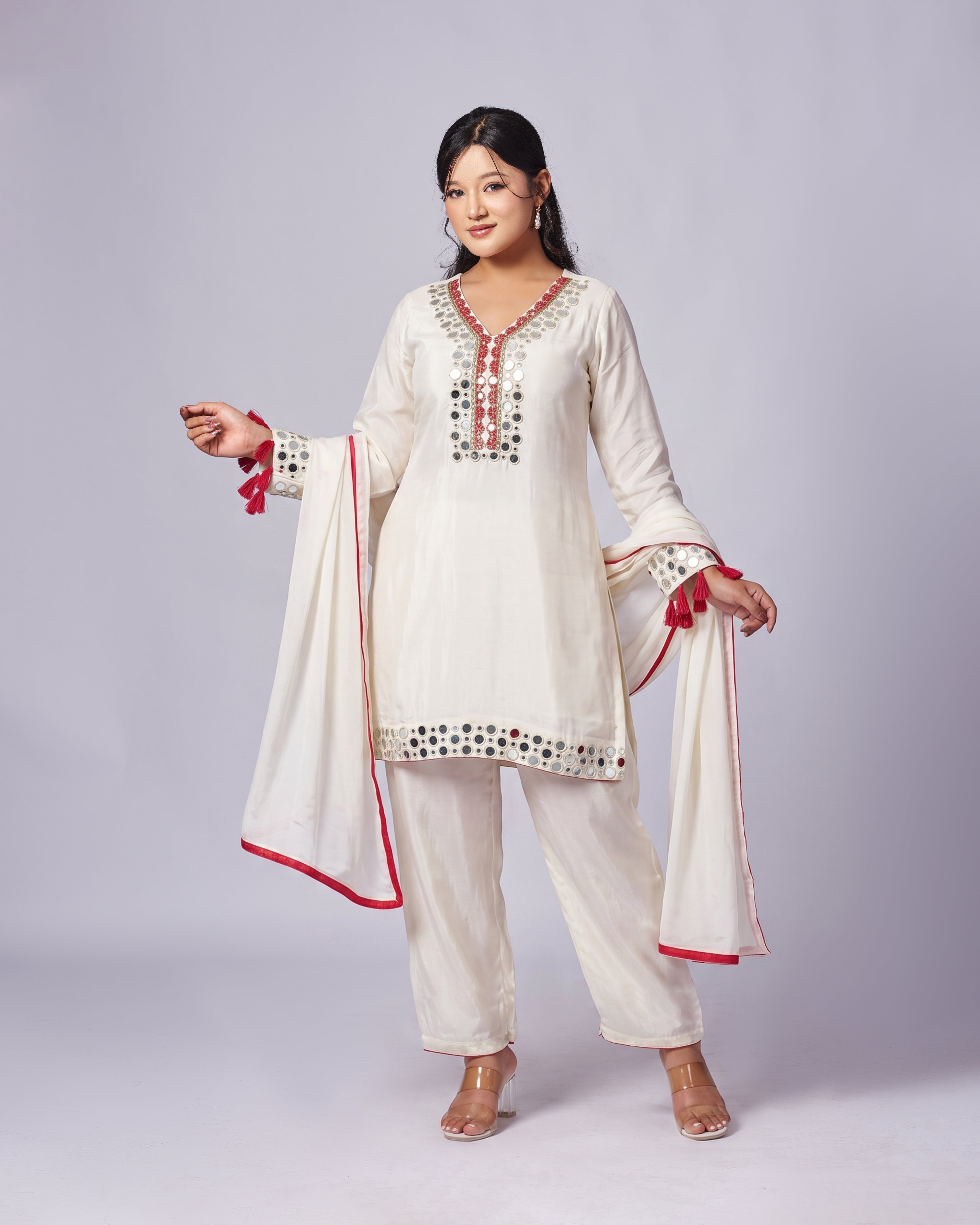 Woman wearing a traditional outfit with white kurta, pants, and dupatta on a light gray background