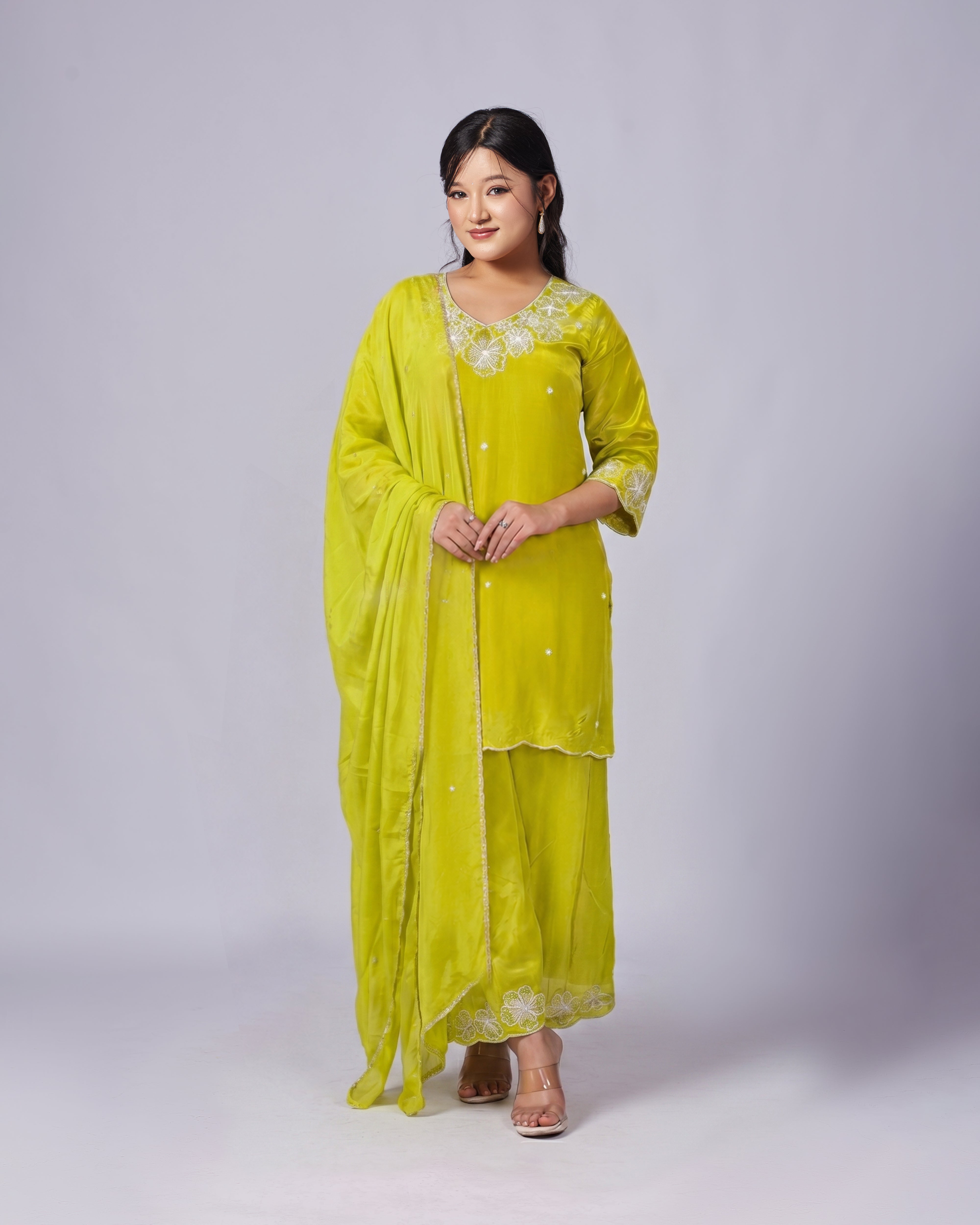 Woman wearing a bright yellow traditional outfit with a plain background