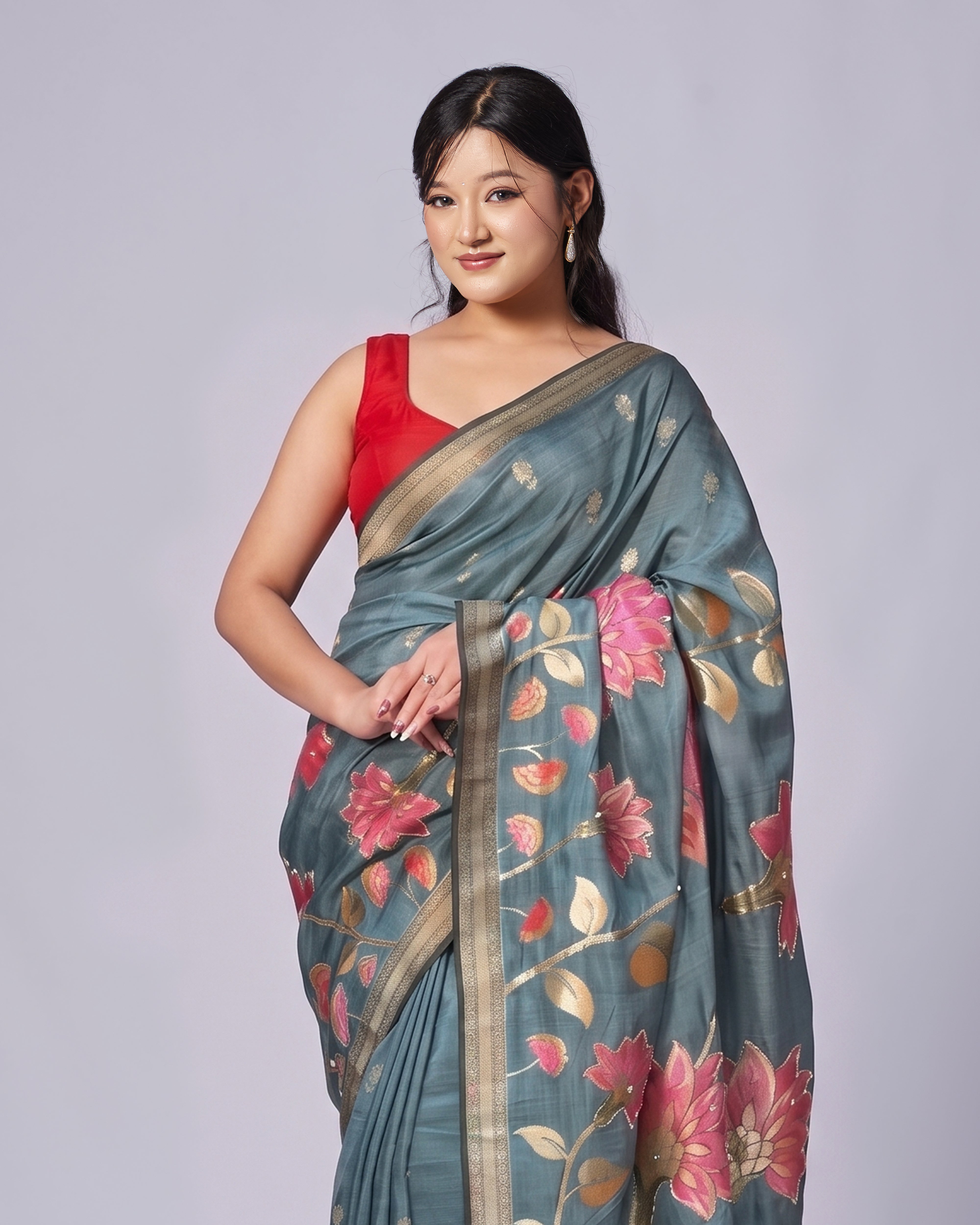 Woman wearing a floral saree with a red blouse on a gray background