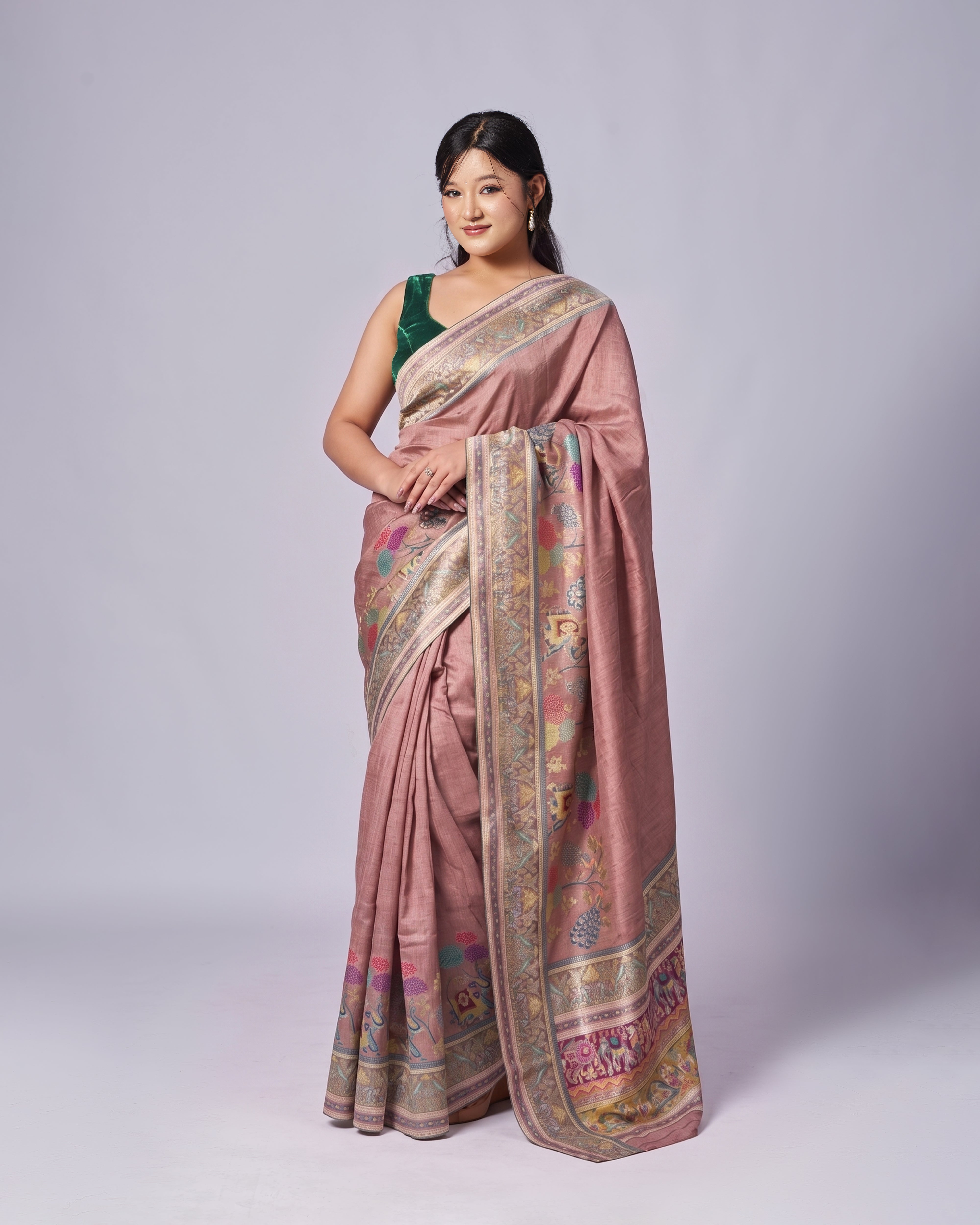 Woman wearing a traditional pink saree with intricate patterns on a white background