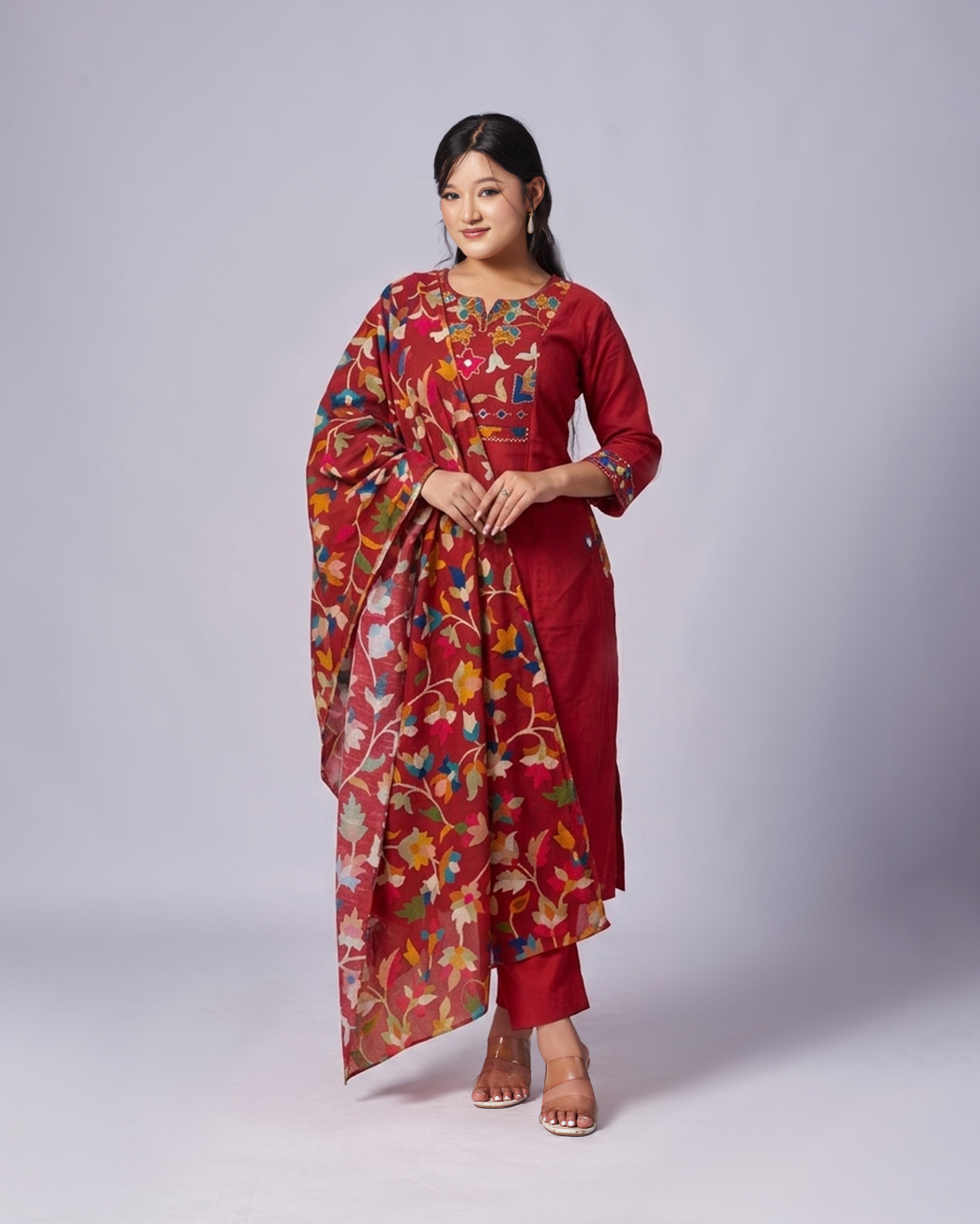 Woman wearing a red floral Kurthi set , a traditional outfit on a white grey background
