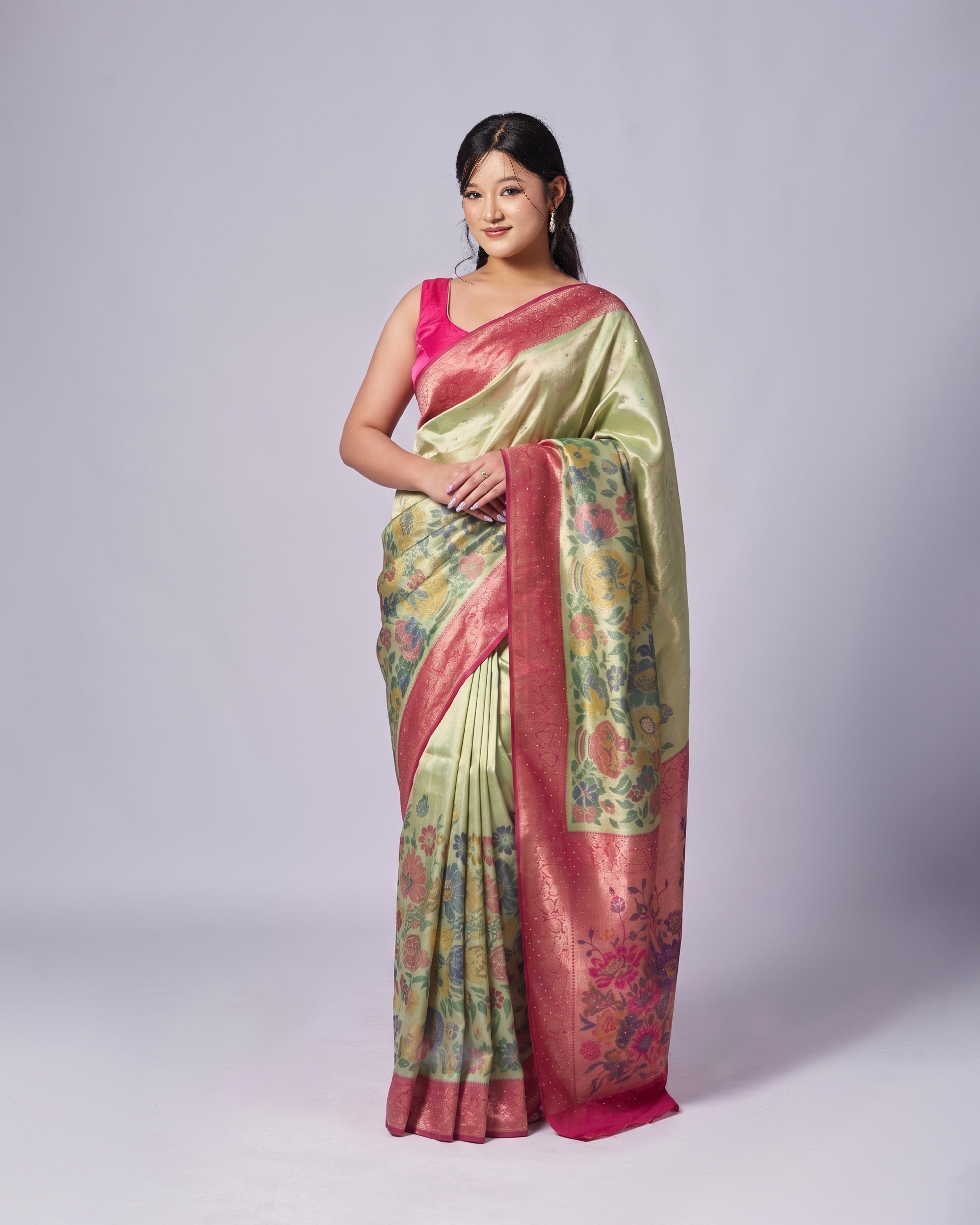 Woman wearing a traditional saree with a floral pattern on a plain background