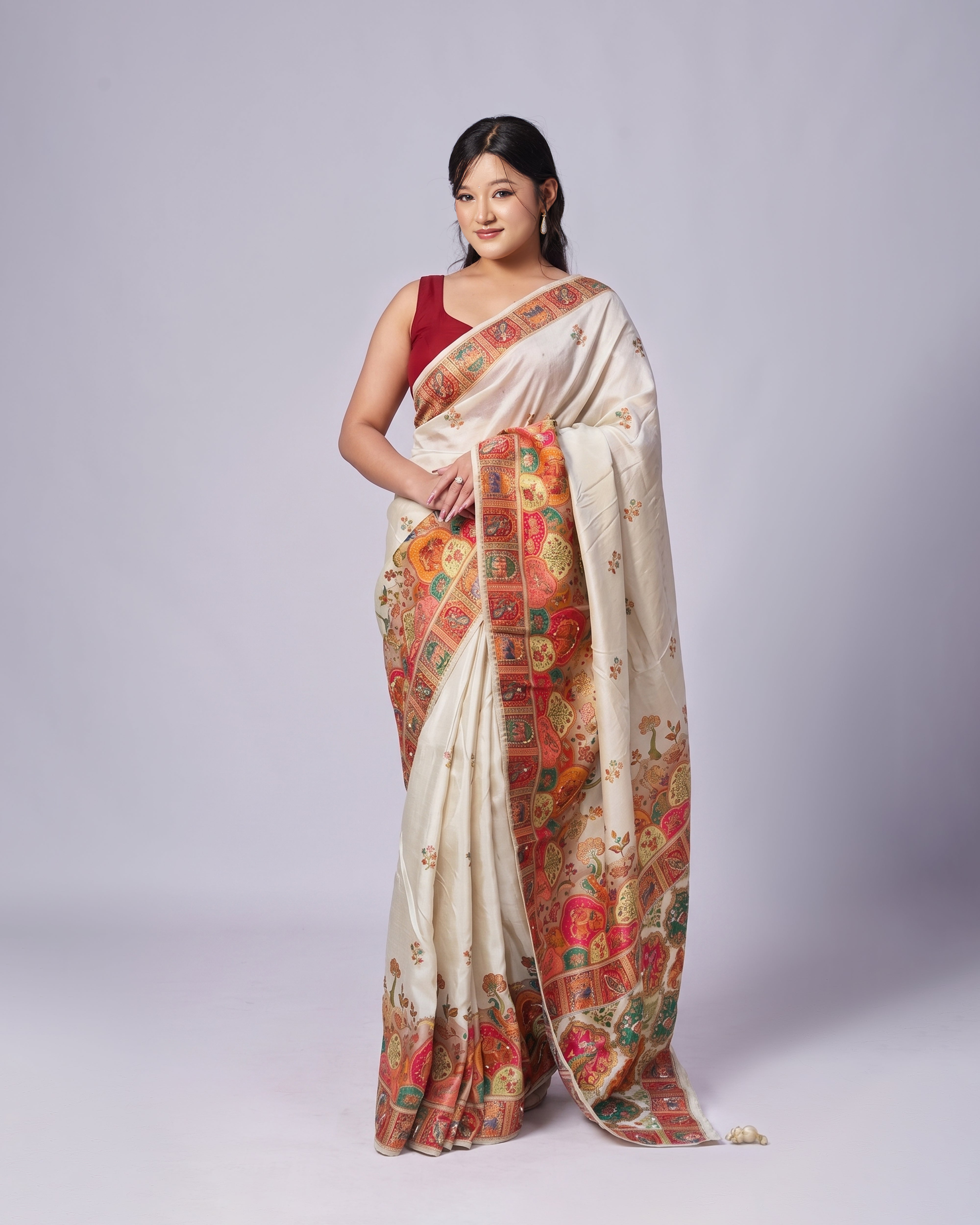 Woman wearing a traditional saree with a colorful pattern on a plain background