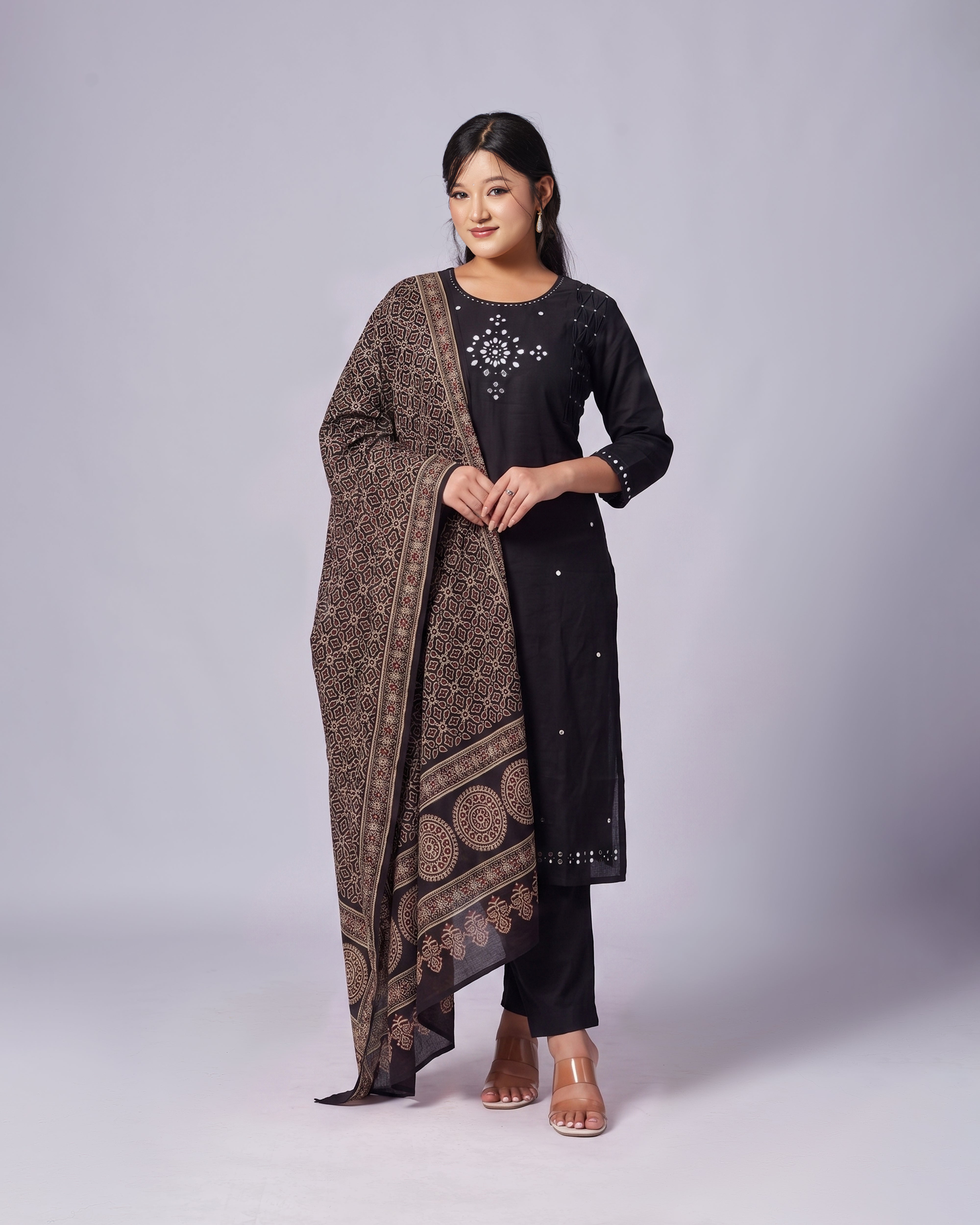 Woman wearing a black kurta with a patterned dupatta on a white background
