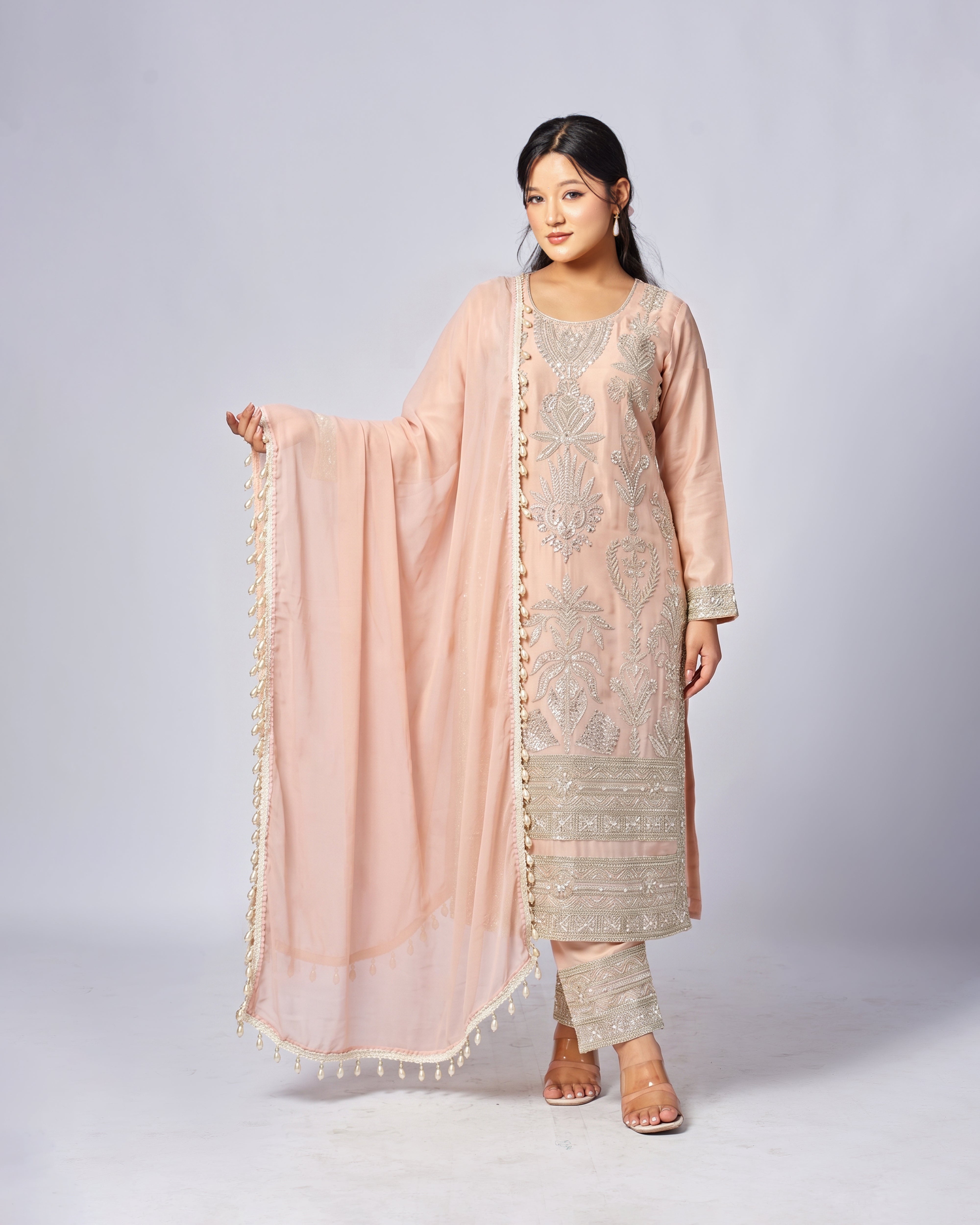 Woman wearing a traditional outfit with a pink dupatta on a white background