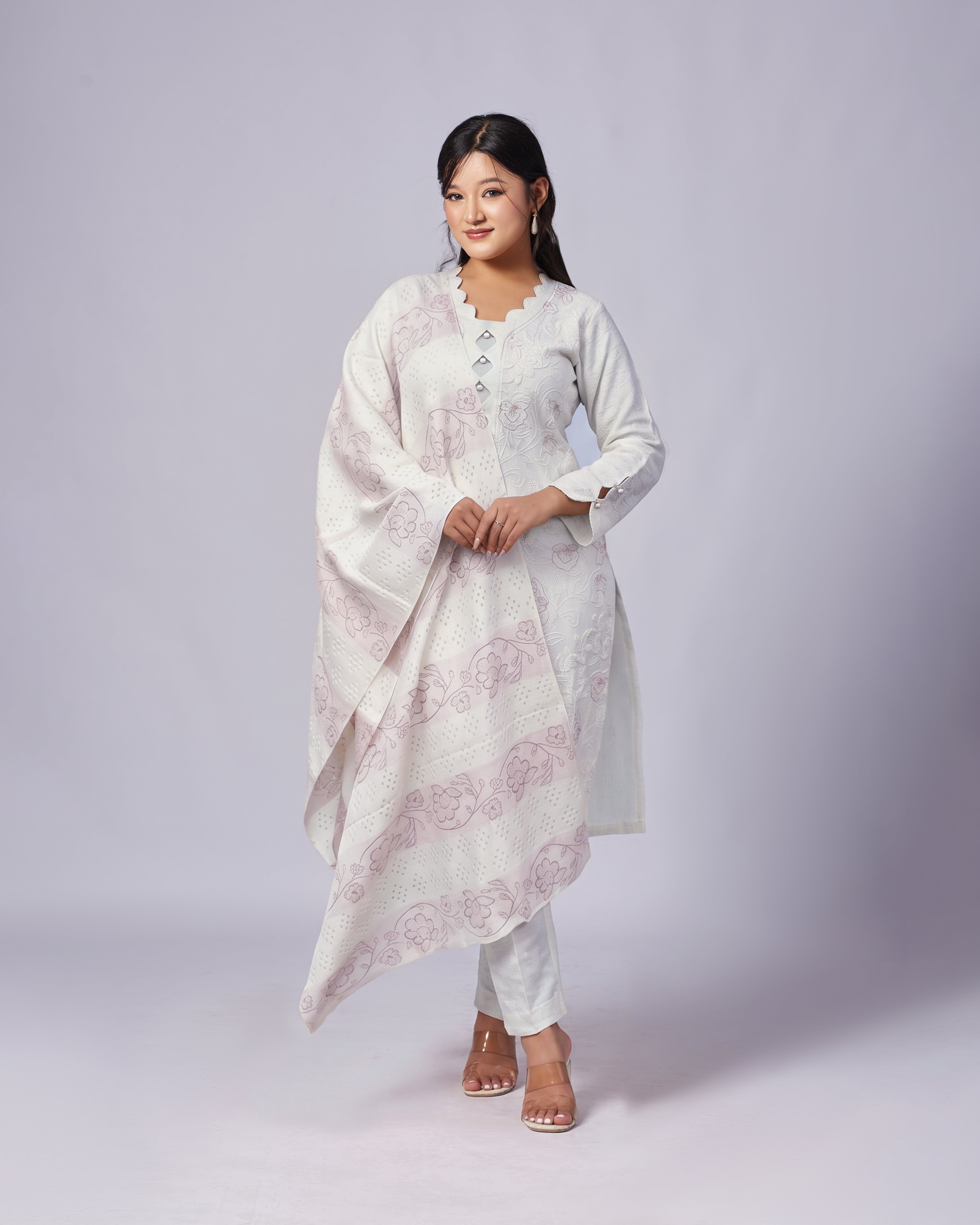 Woman wearing a white floral kurta with a matching dupatta on a plain background