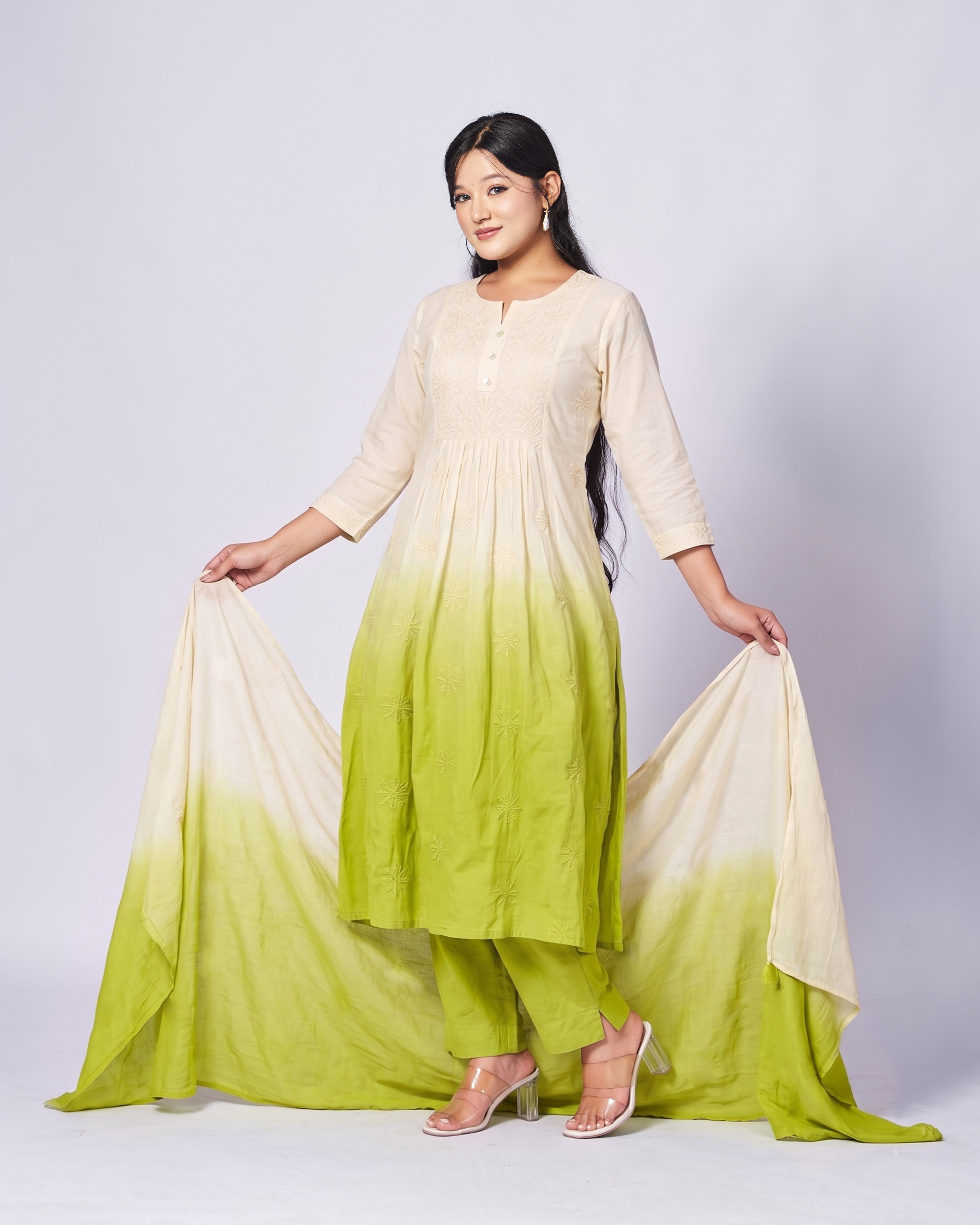 Woman wearing a light green and white ombre outfit on a plain background
