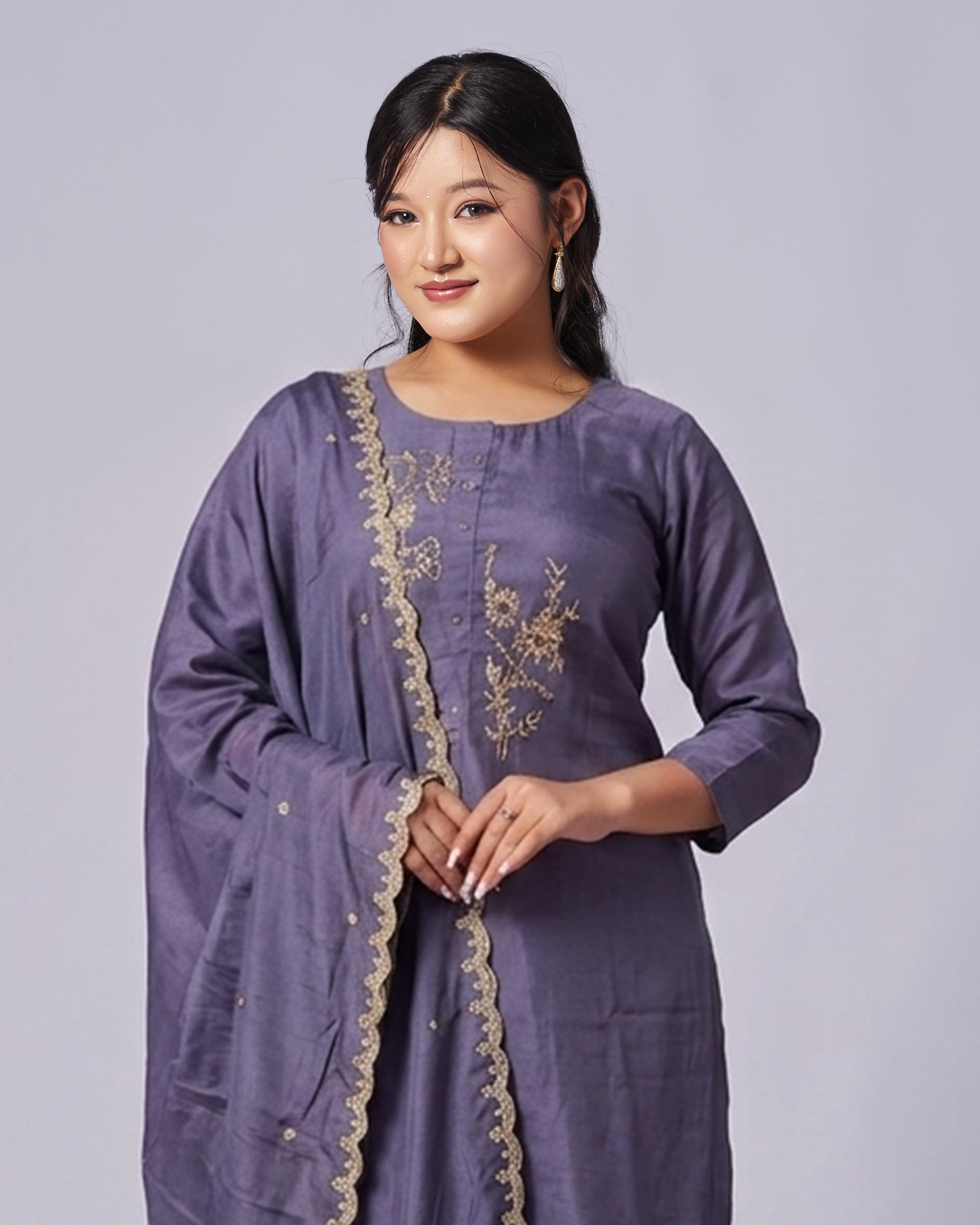 Woman wearing a purple embroidered dress on a plain background
