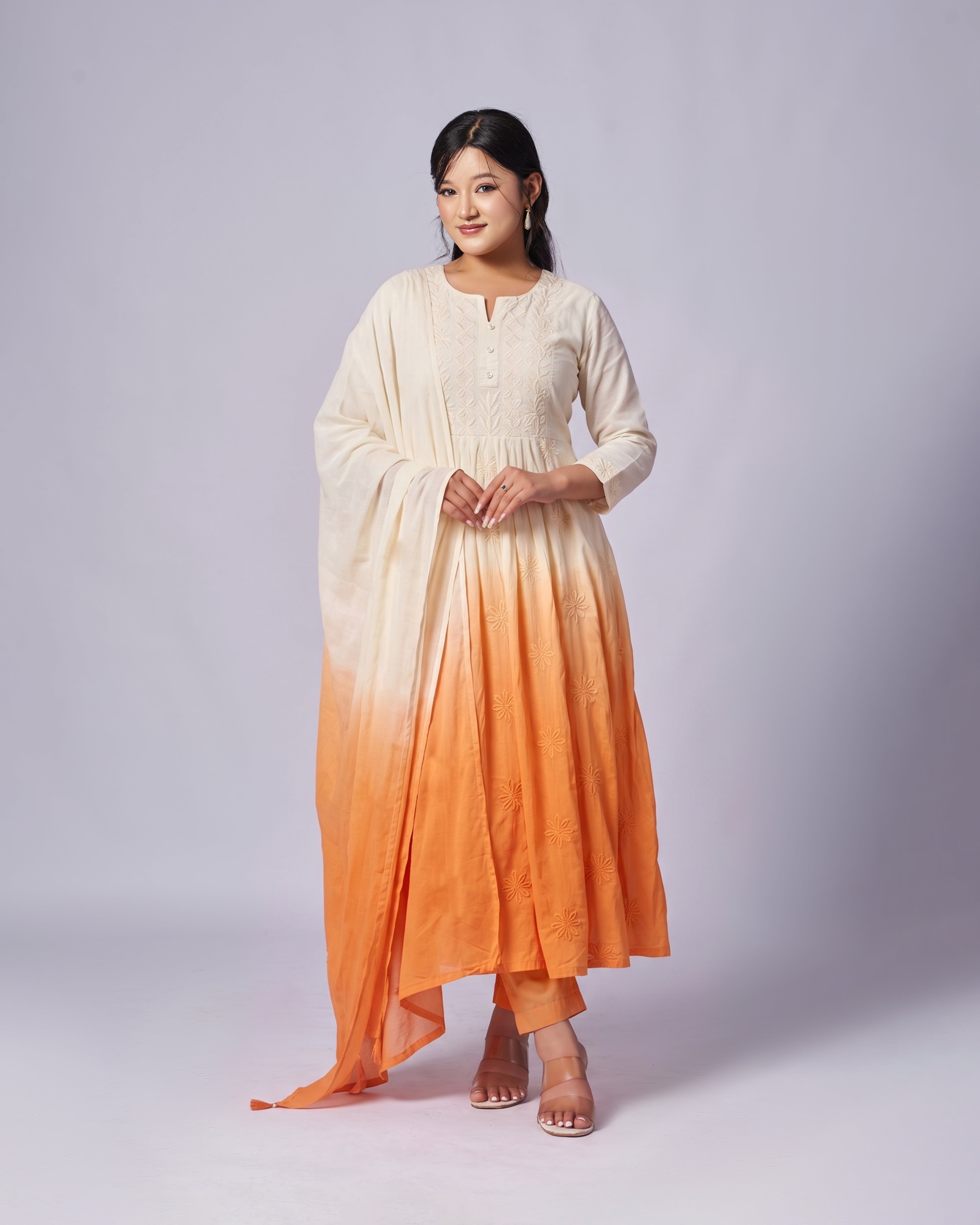 Woman wearing a white and orange gradient dress on a plain background