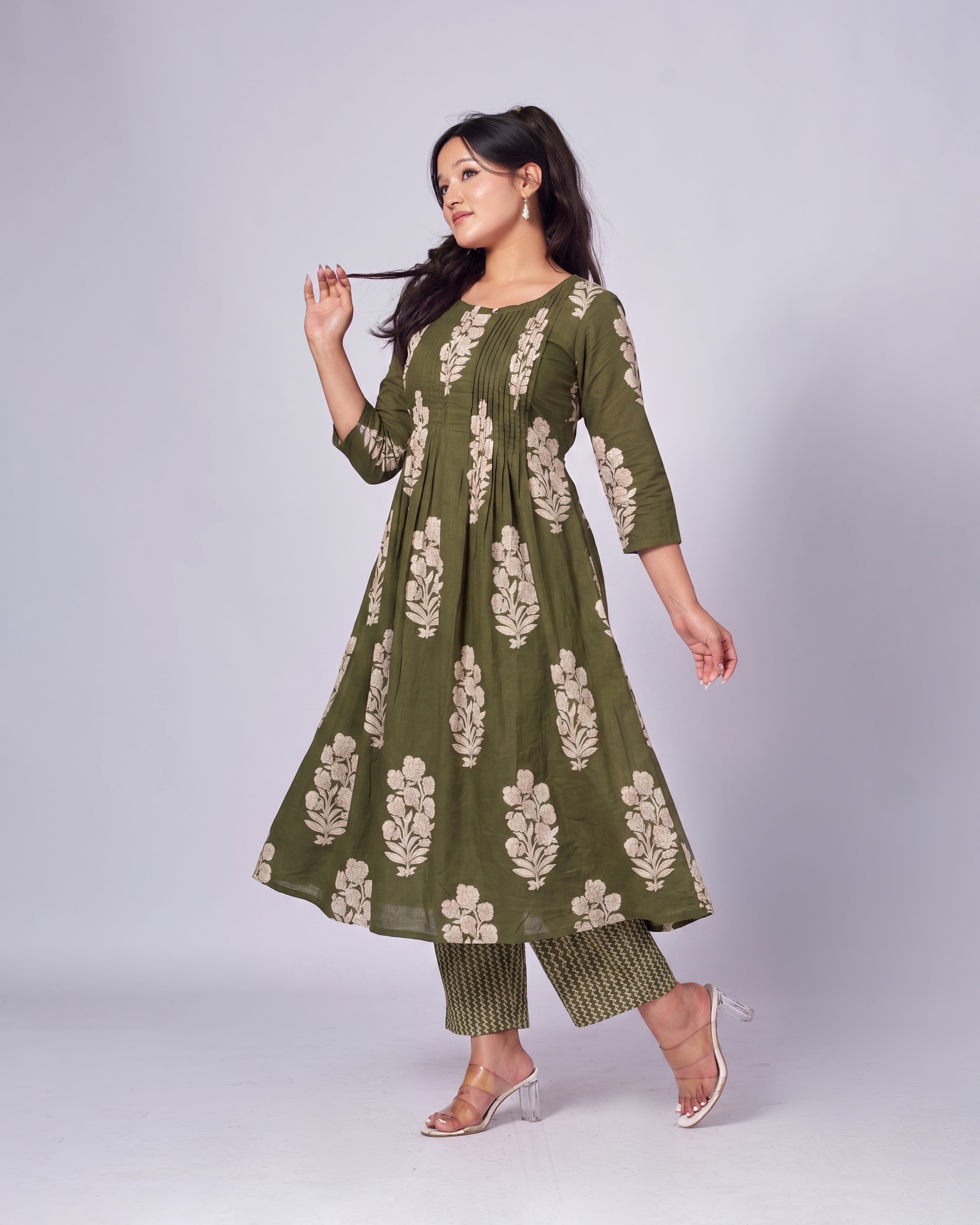 Woman wearing a green floral dress and pants on a white background