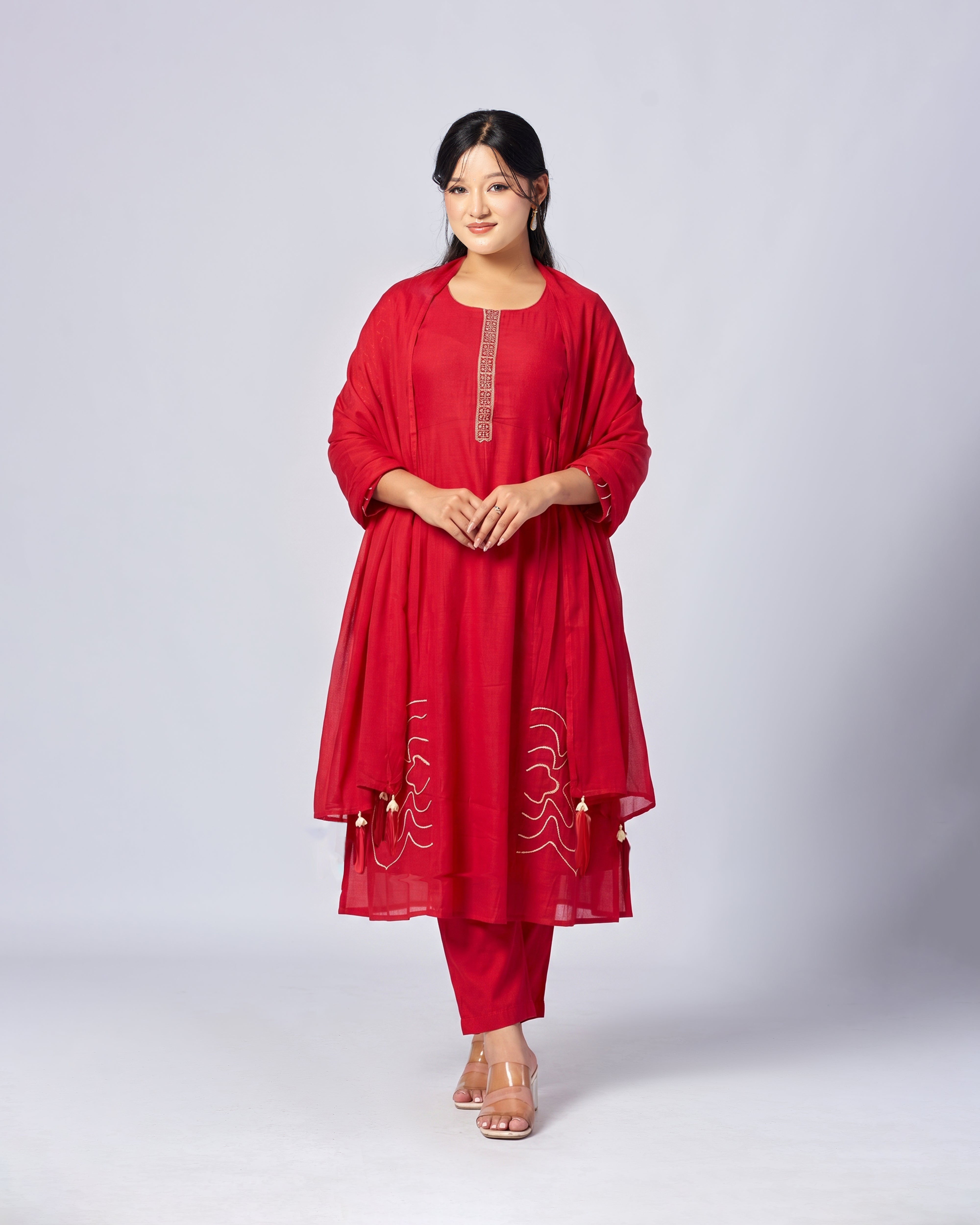 Woman wearing a red traditional outfit with intricate designs on a white background