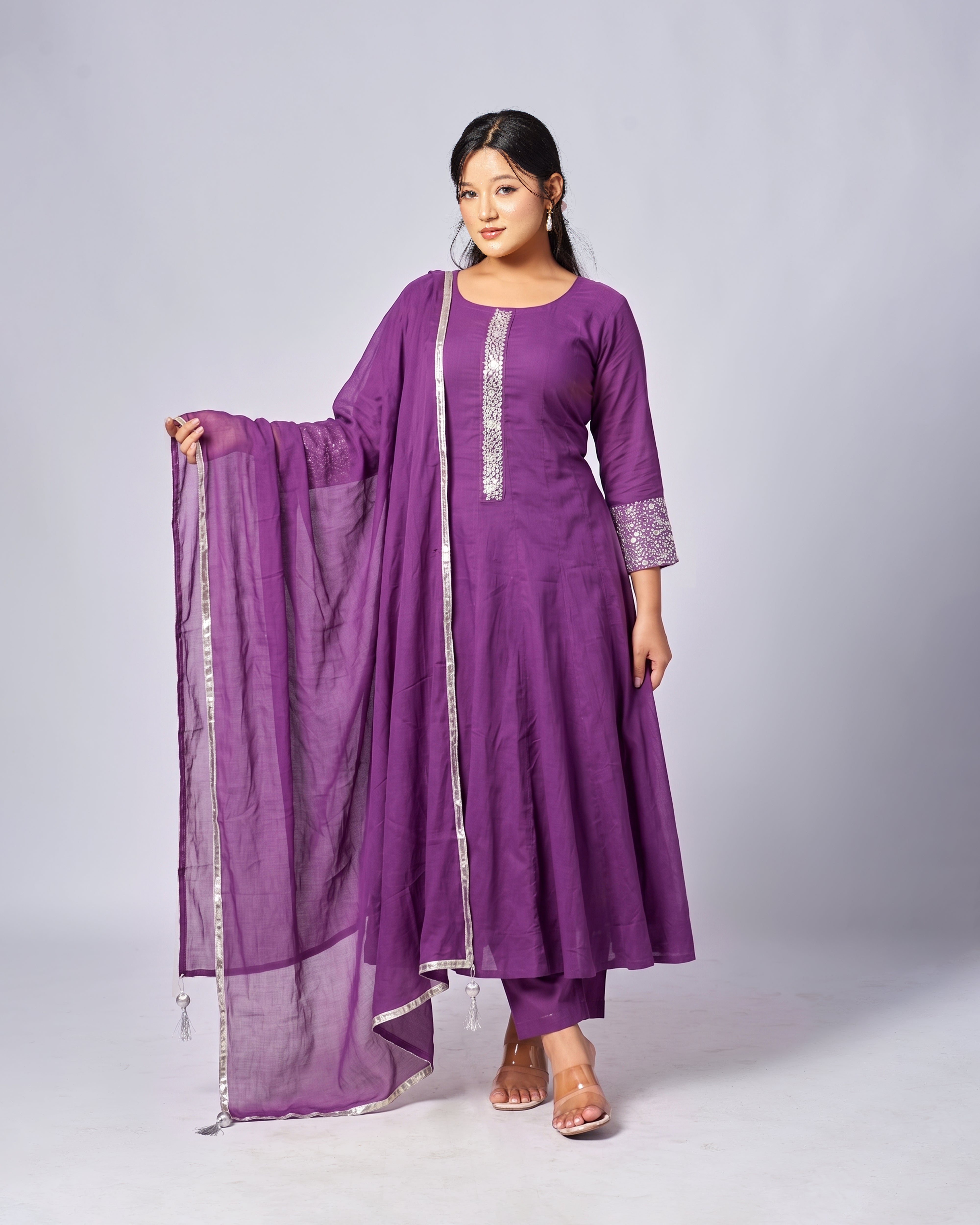 Woman wearing a purple traditional outfit with a scarf on a gray background