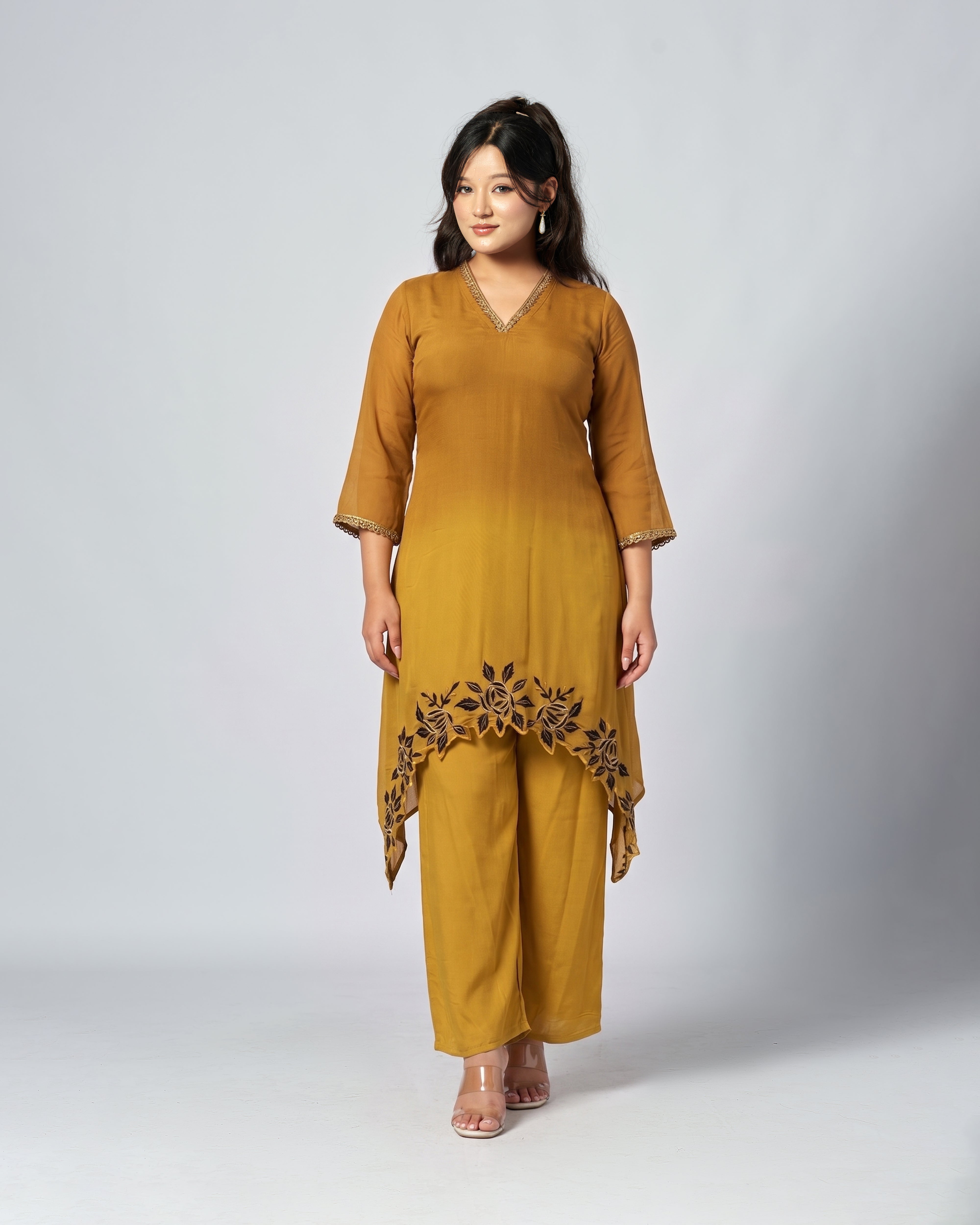 Woman wearing a mustard yellow outfit with floral details on a white background