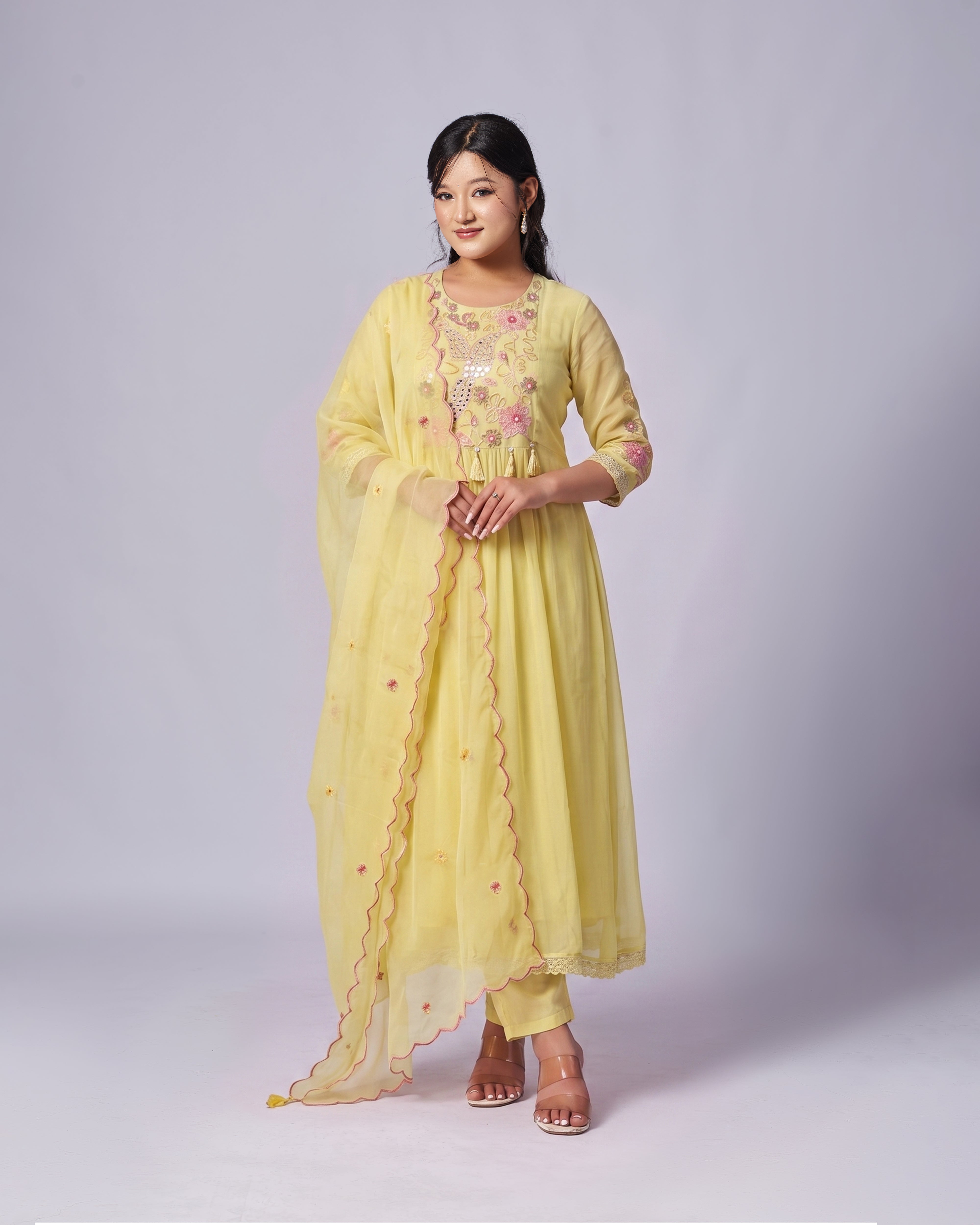 Woman wearing a yellow embroidered traditional outfit on a white background