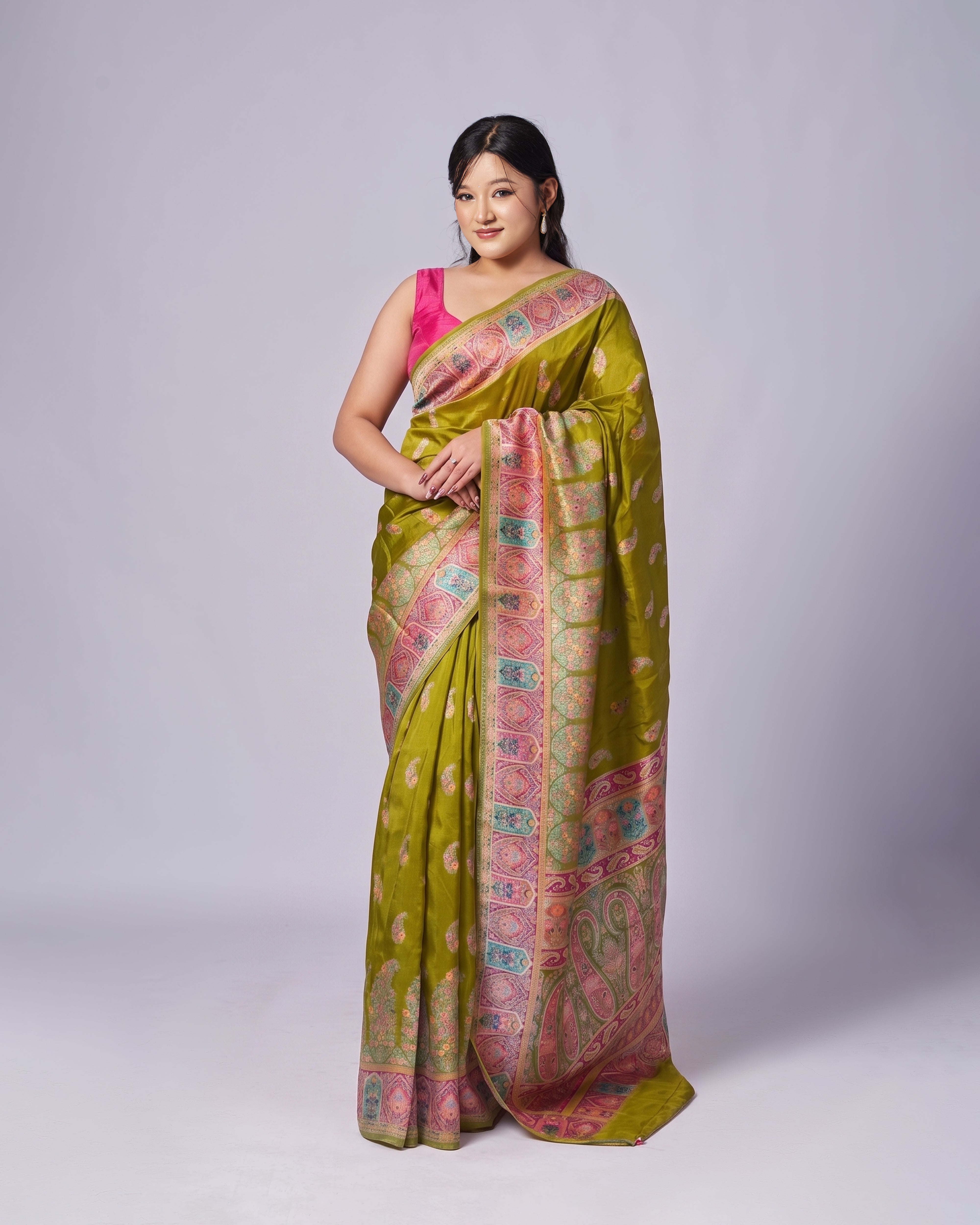 Woman wearing a green and pink saree with a white background
