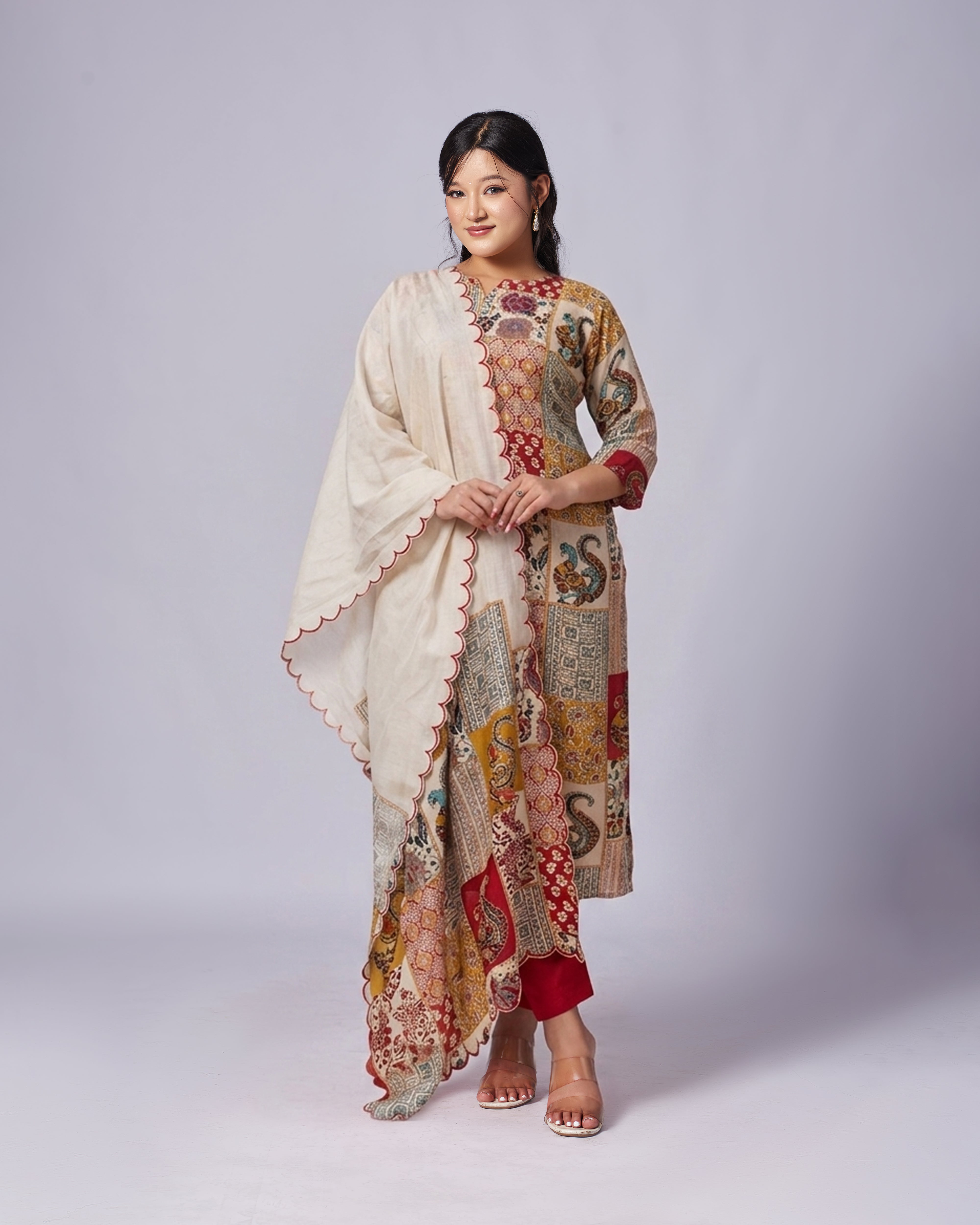 Woman wearing a traditional outfit with a patterned shawl on a plain background