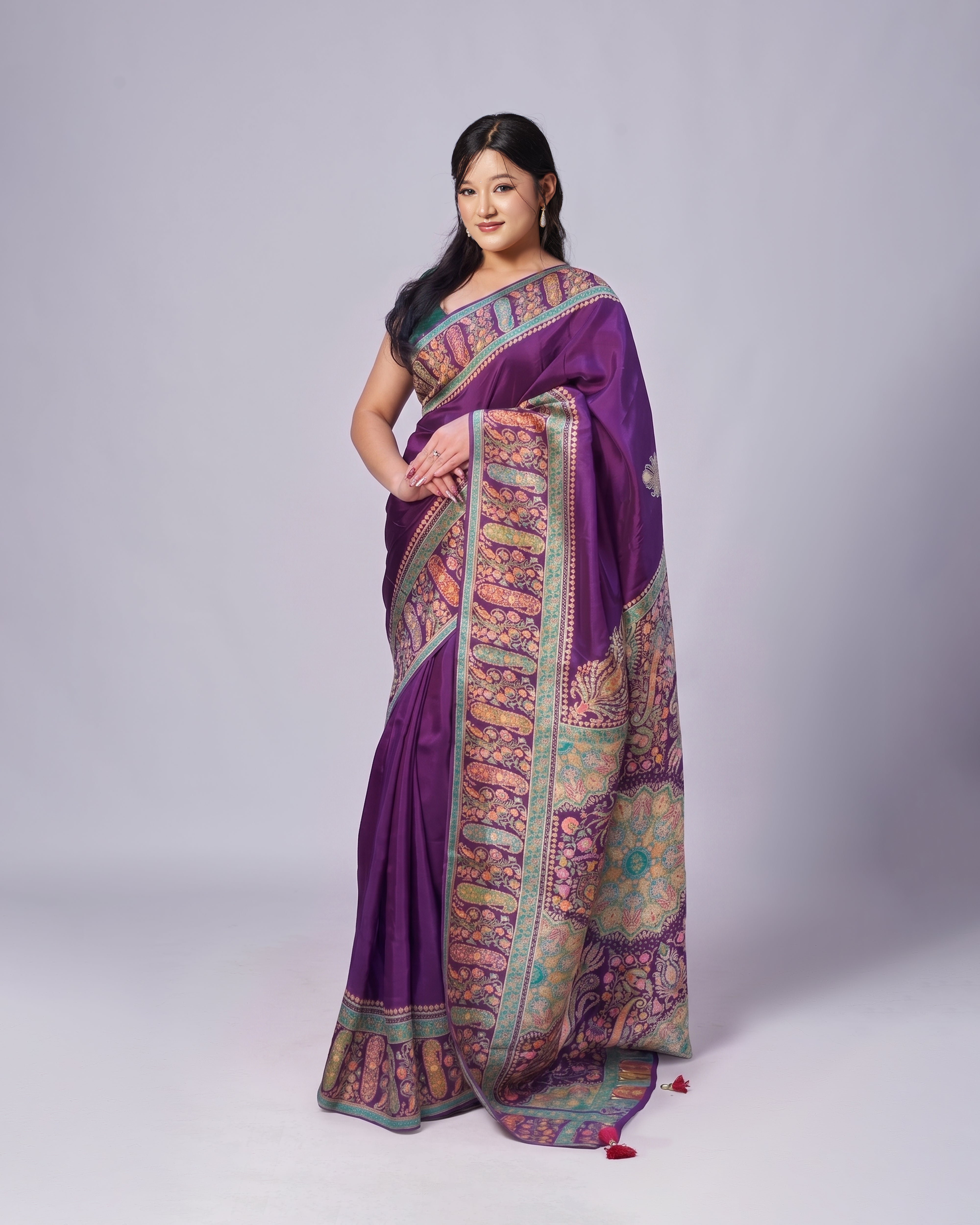 Woman wearing a purple saree with intricate patterns on a white background