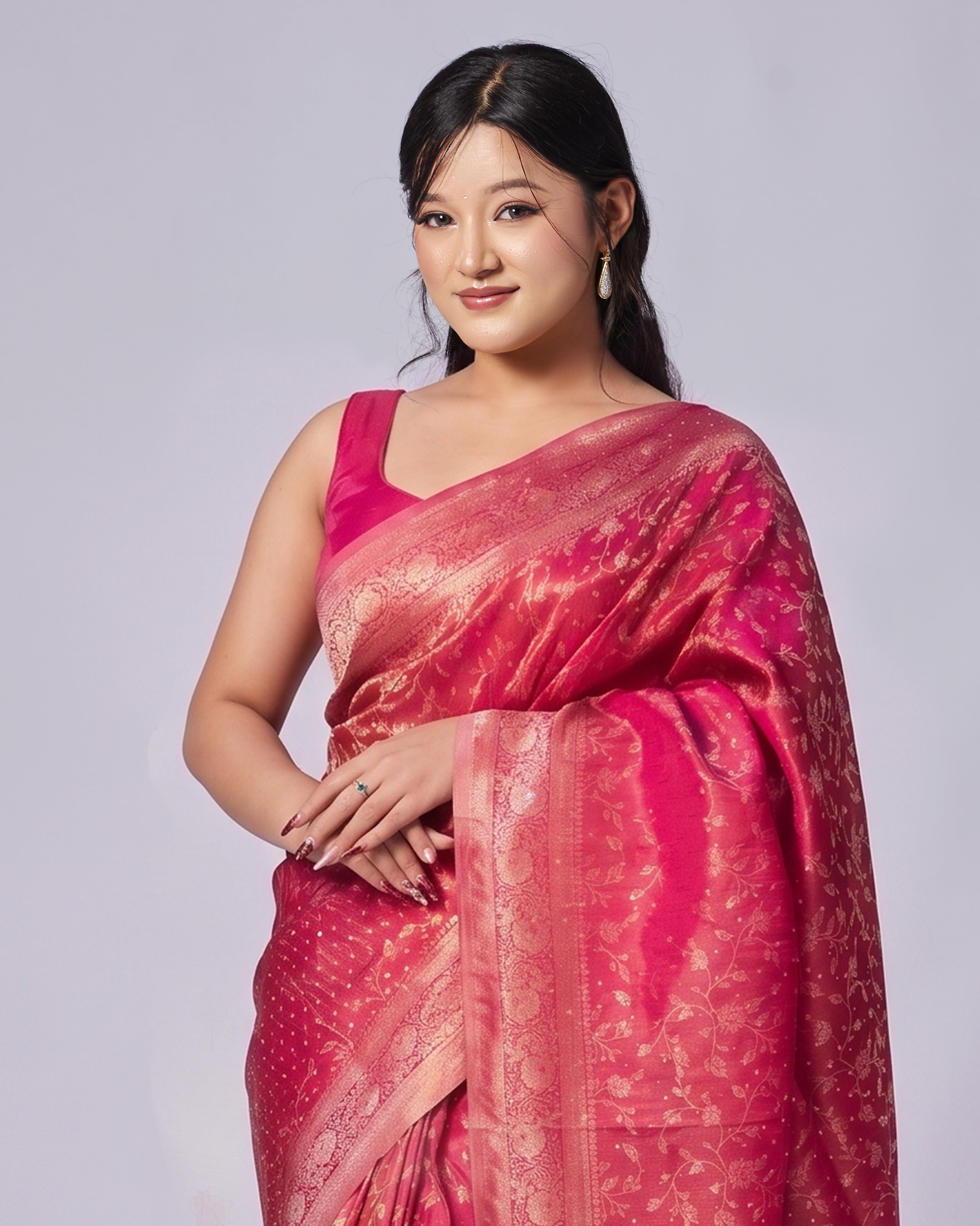 Woman wearing a pink saree with a subtle pattern on a light gray background